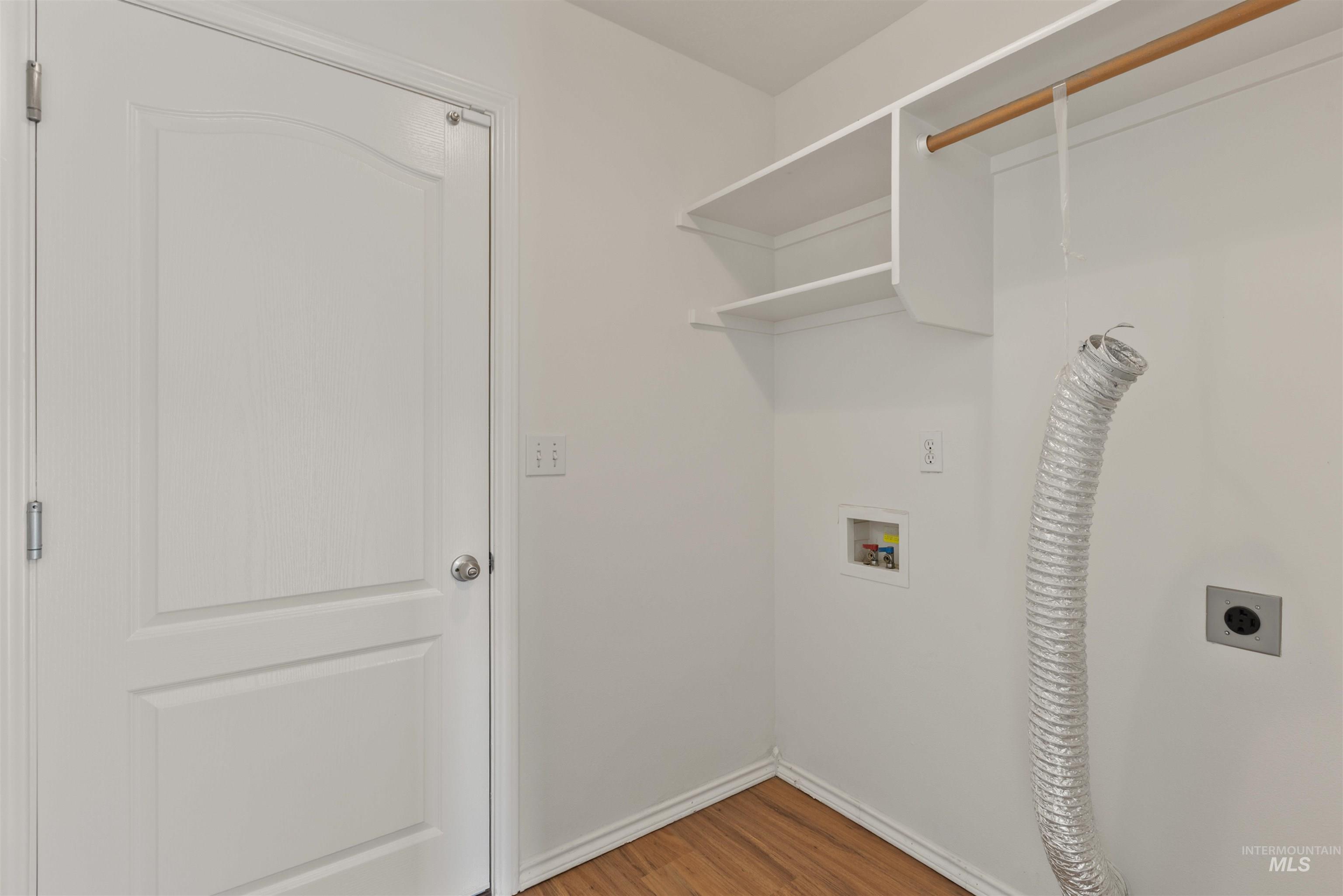 Laundry area with wood finished floors, hookup for a washing machine, and electric dryer hookup