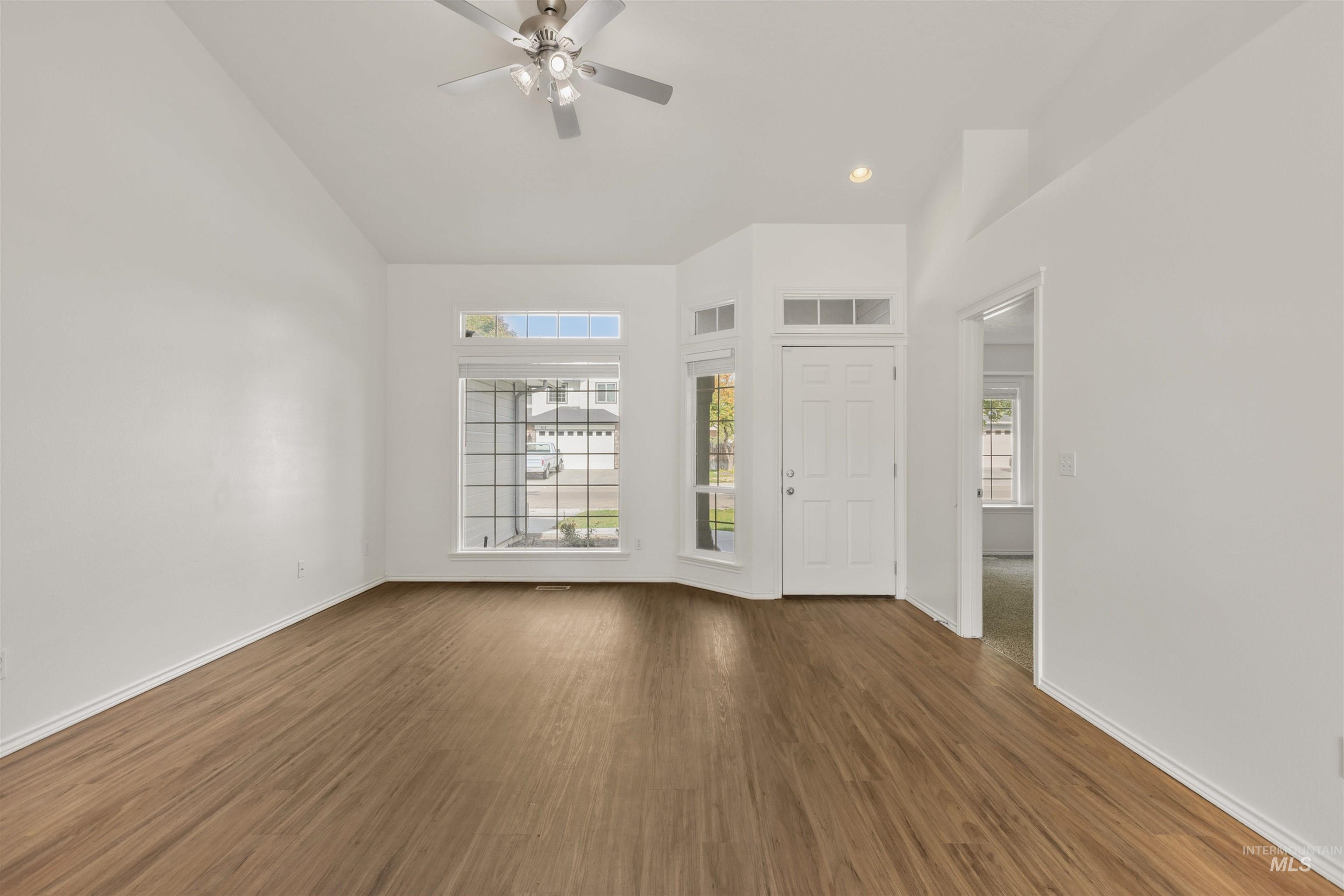 Unfurnished living room featuring dark wood-type flooring, ceiling fan, and recessed lighting