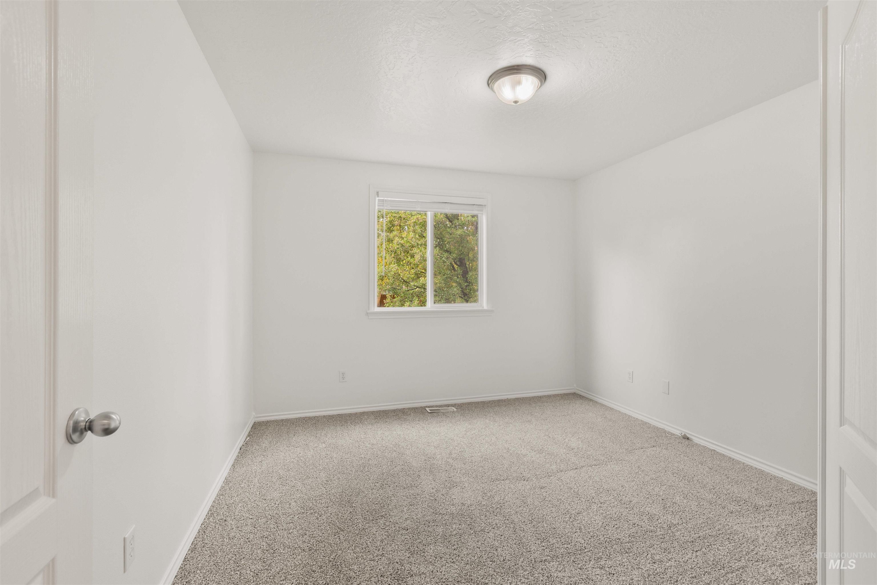 Carpeted empty room with baseboards and a textured ceiling