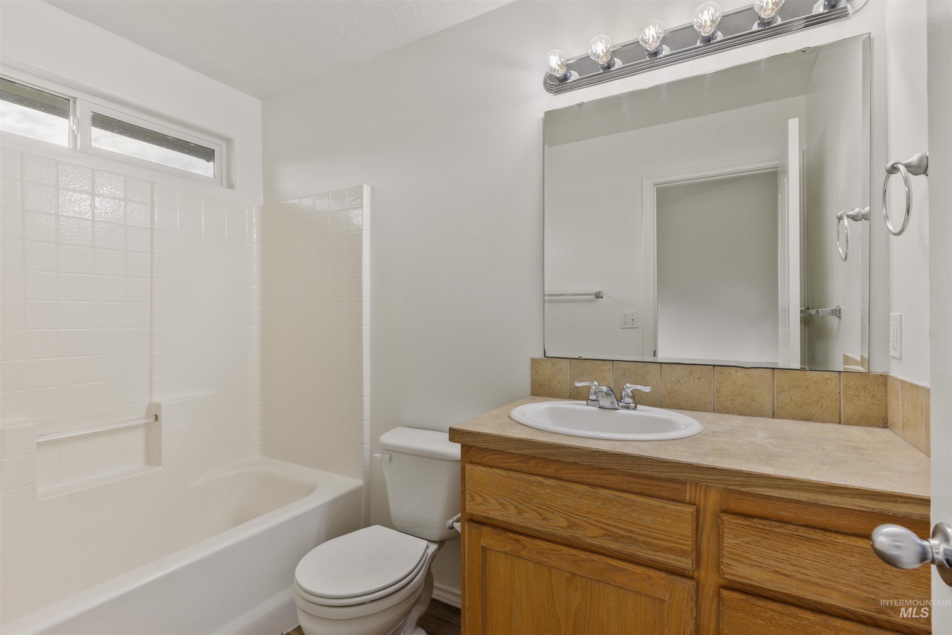 Bathroom with vanity, shower / bathtub combination, and decorative backsplash