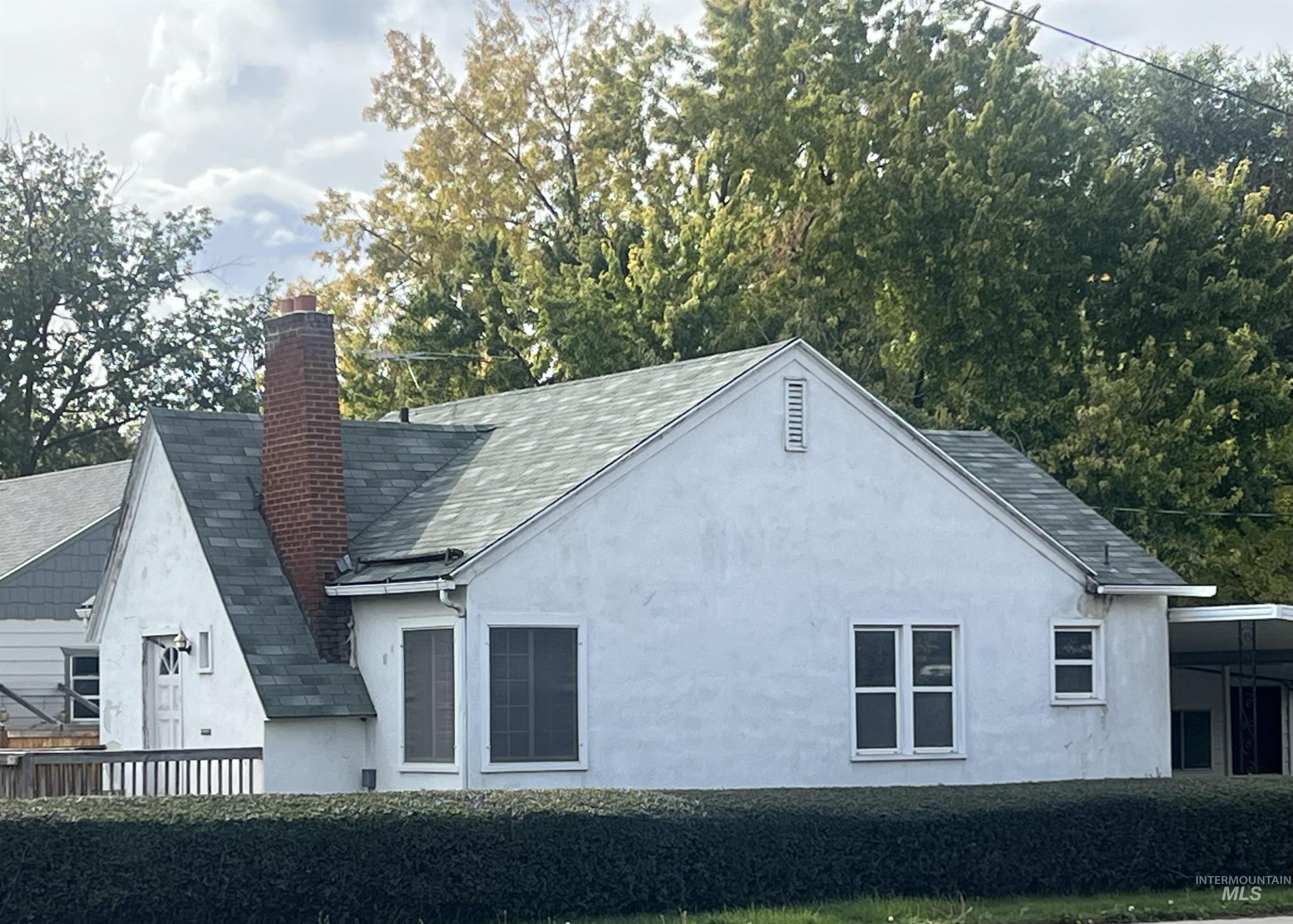 View of home's exterior featuring stucco siding, a chimney, a shingled roof, and an attached carport