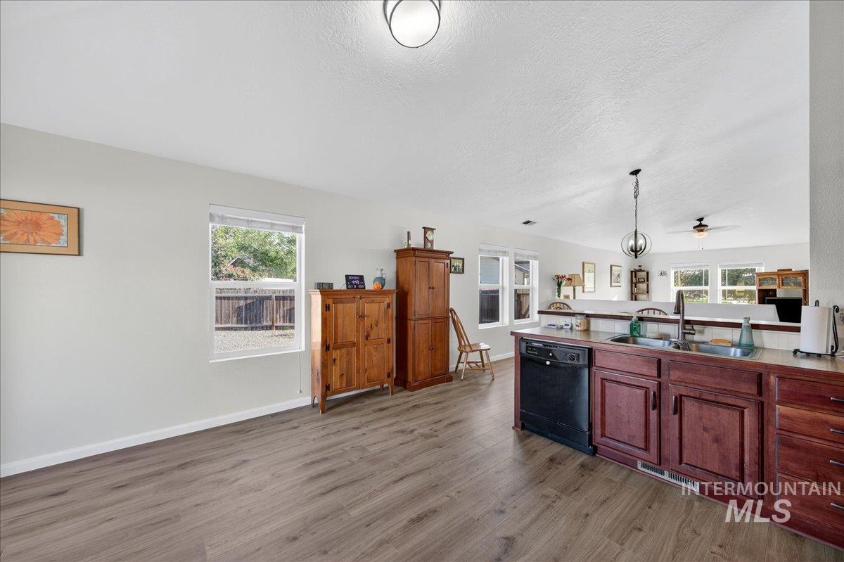 Kitchen with pendant lighting, dark wood finished floors, dishwasher, a ceiling fan, and a textured ceiling