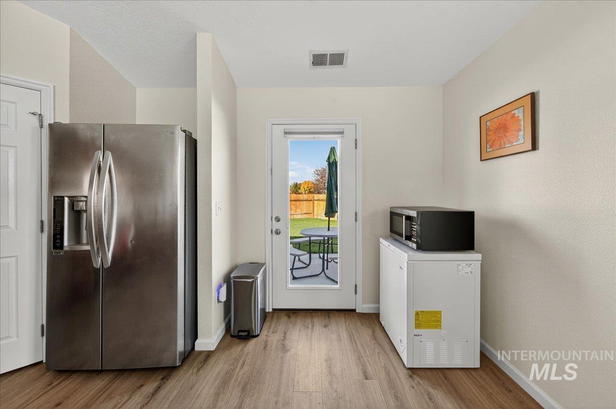 Kitchen featuring stainless steel fridge with ice dispenser, light wood-type flooring, and white fridge