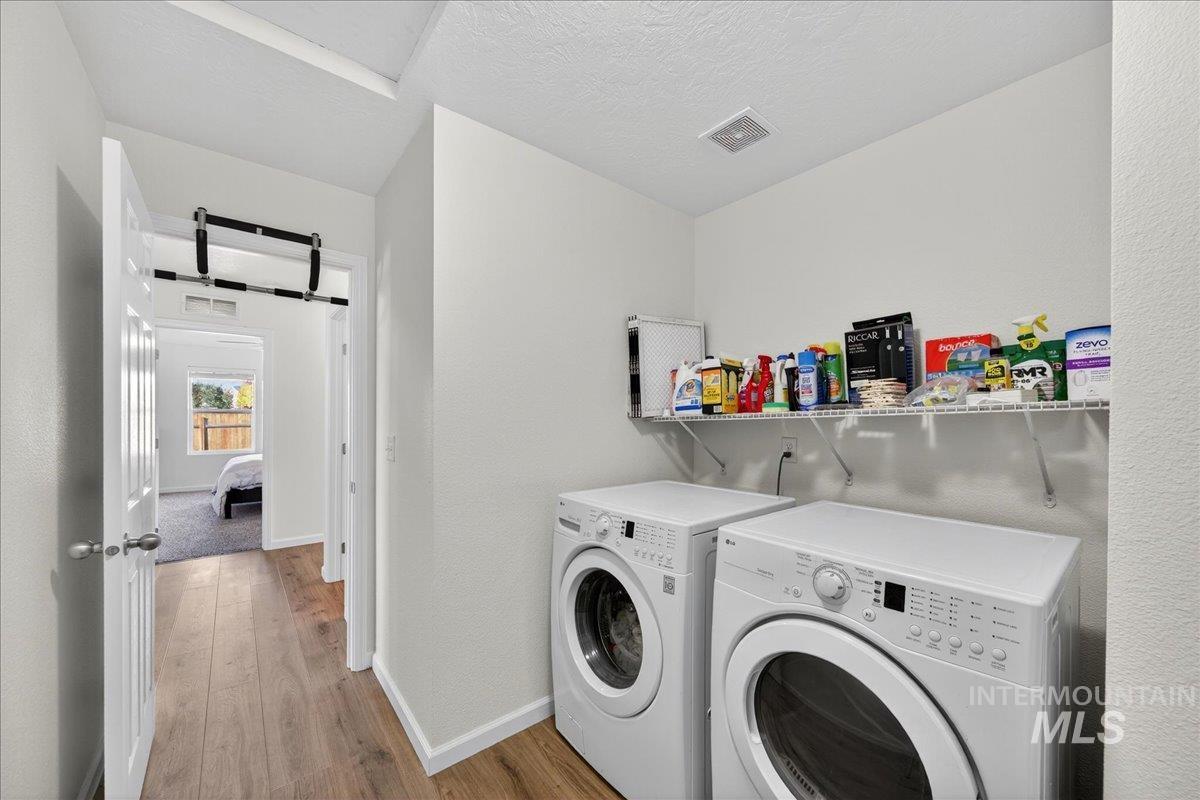Washroom featuring wood finished floors, separate washer and dryer, a textured ceiling, and a textured wall