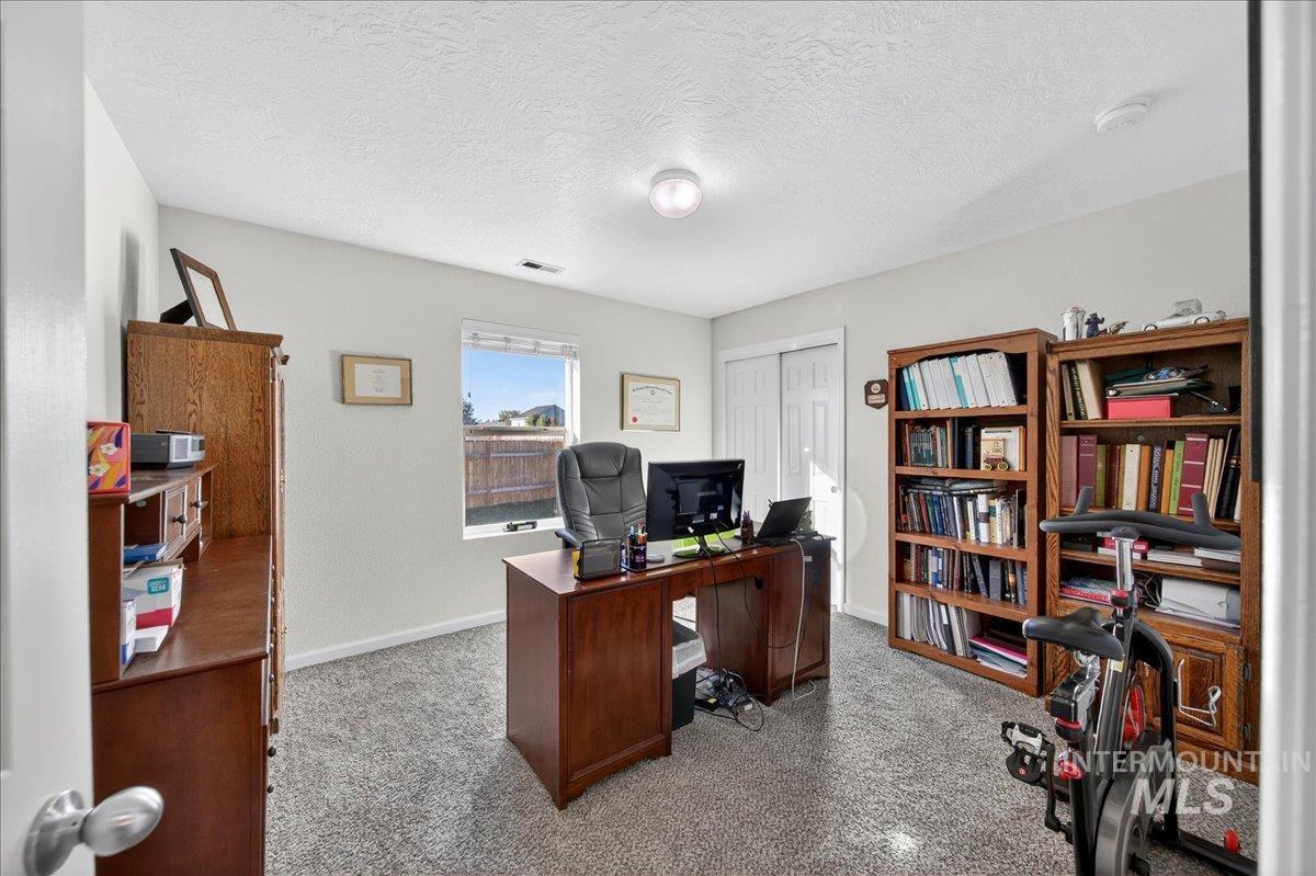 Office with a textured ceiling and light carpet