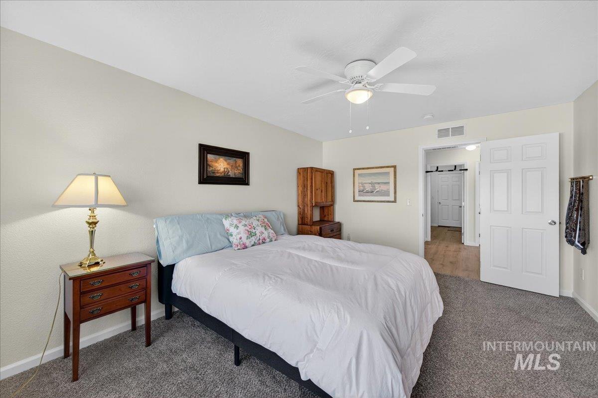 Carpeted bedroom with a ceiling fan and baseboards