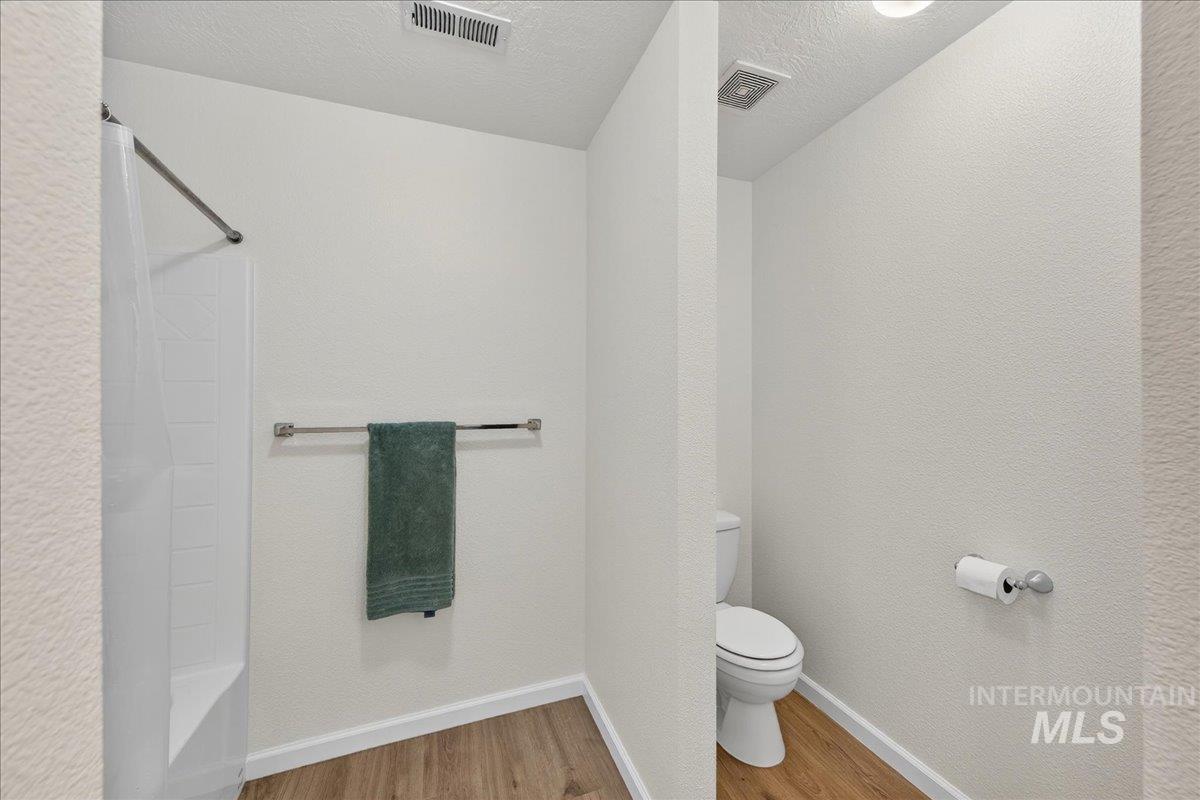 Full bath featuring wood finished floors, a textured ceiling,  shower combination, and a textured wall