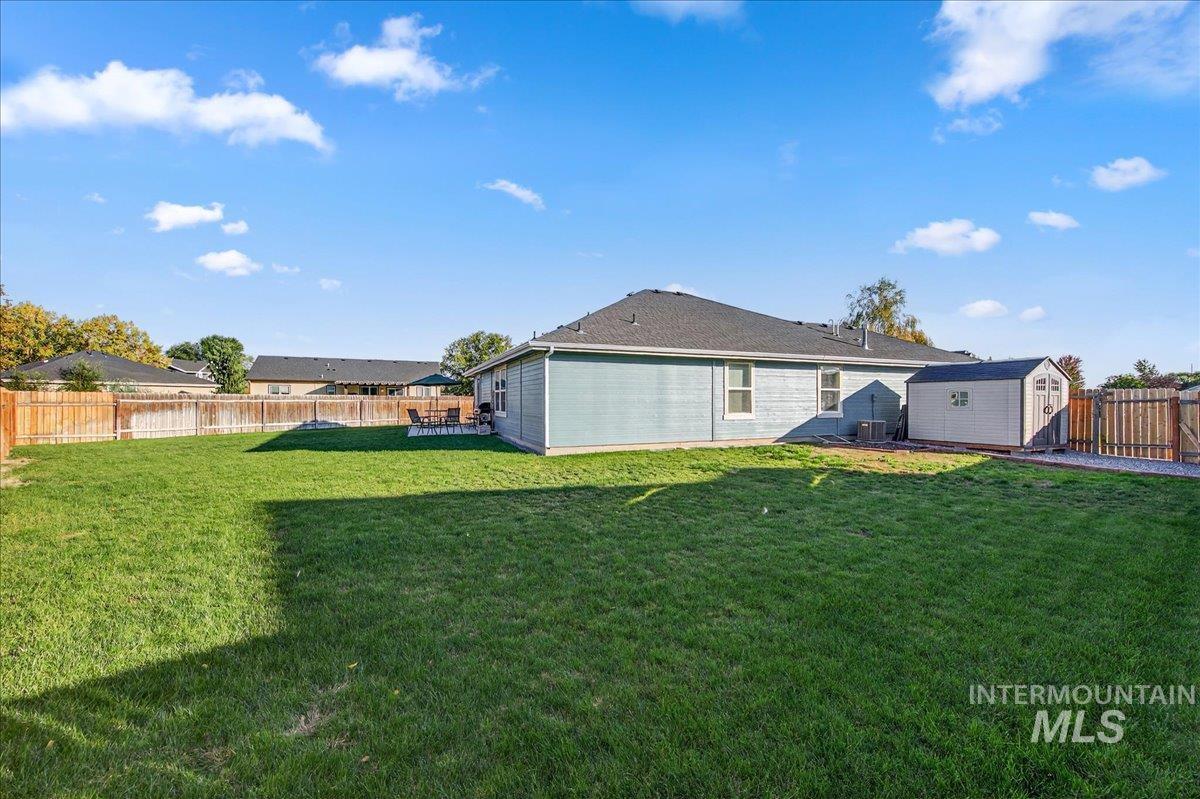 Rear view of house featuring a fenced backyard and a storage unit