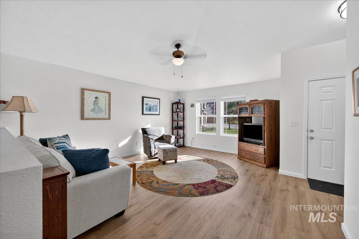 Living room with light wood-style floors, a ceiling fan, and a textured ceiling