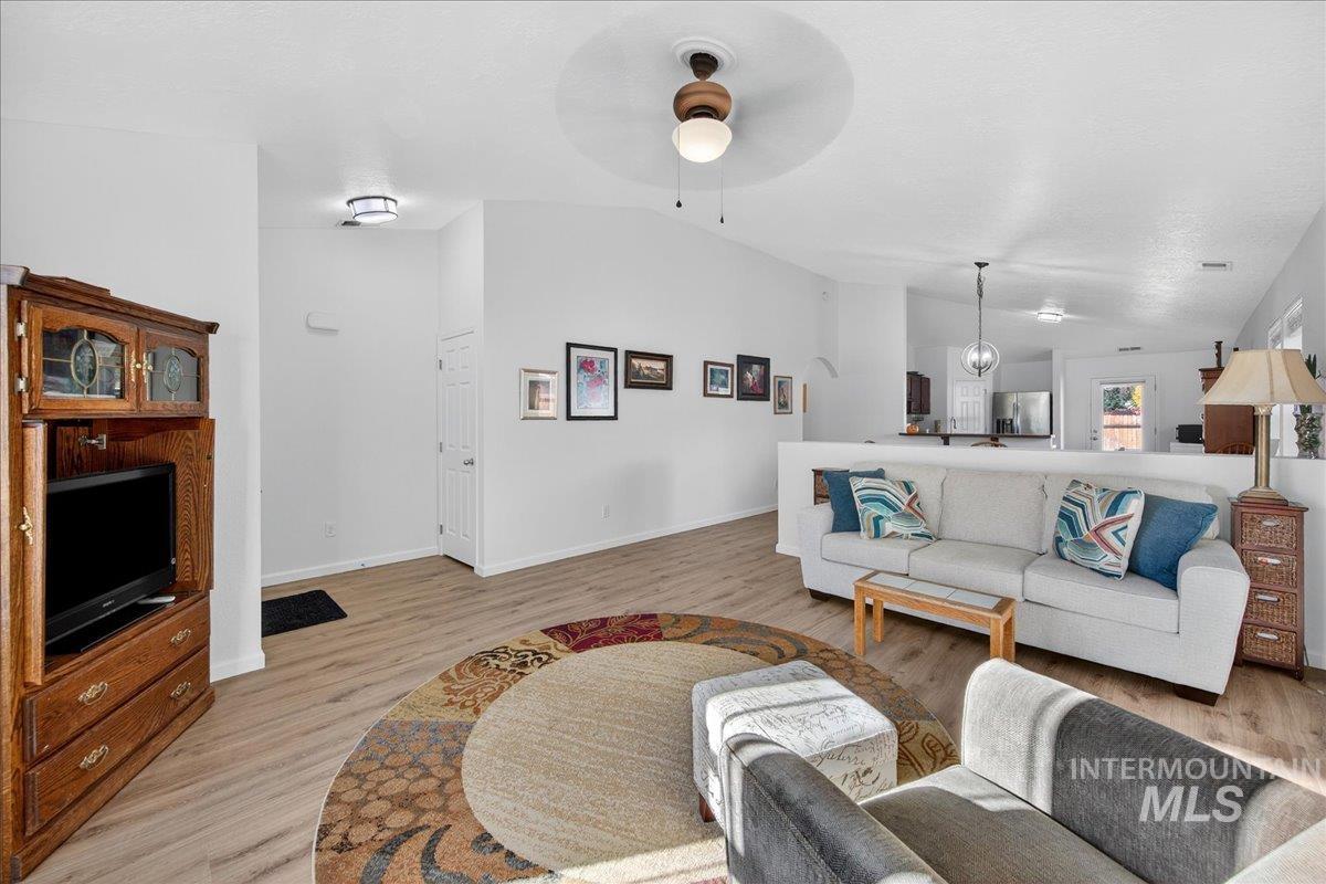 Living room with vaulted ceiling, light wood-style flooring, and a ceiling fan