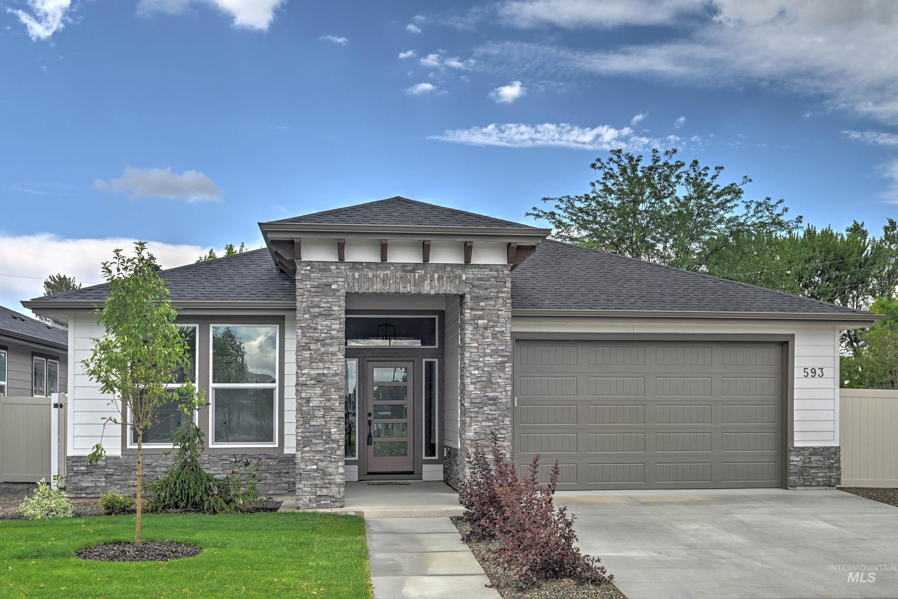 Prairie-style home featuring stone siding, concrete driveway, an attached garage, a shingled roof, and a front yard