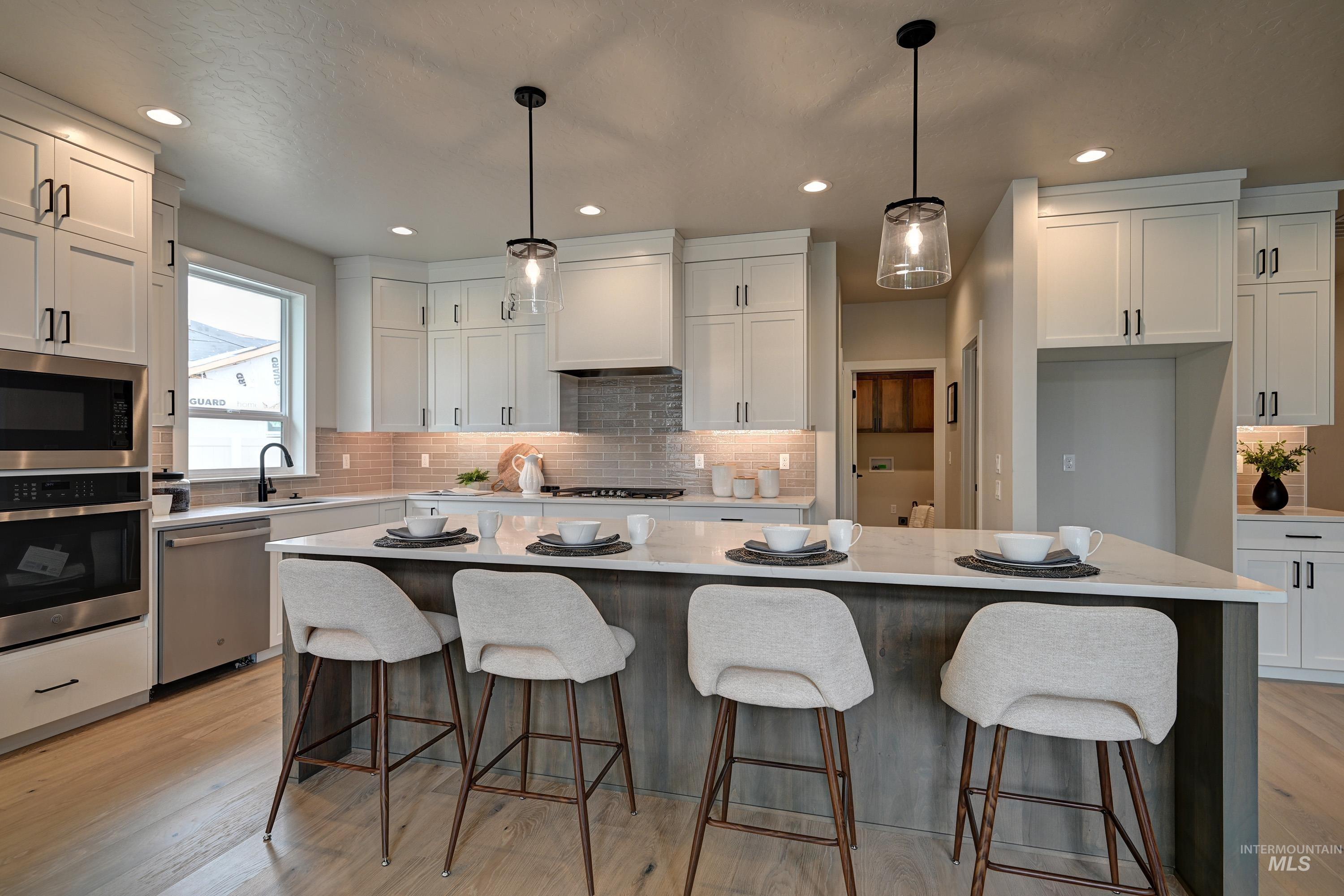 Kitchen with appliances with stainless steel finishes, white cabinetry, decorative backsplash, and recessed lighting