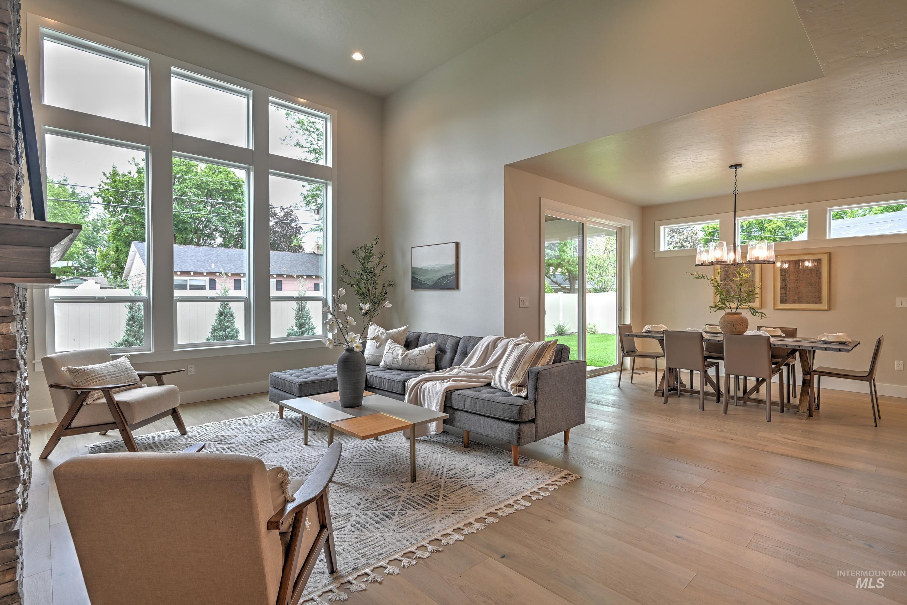 Living room featuring a chandelier, healthy amount of natural light, light wood-type flooring, recessed lighting, and a towering ceiling