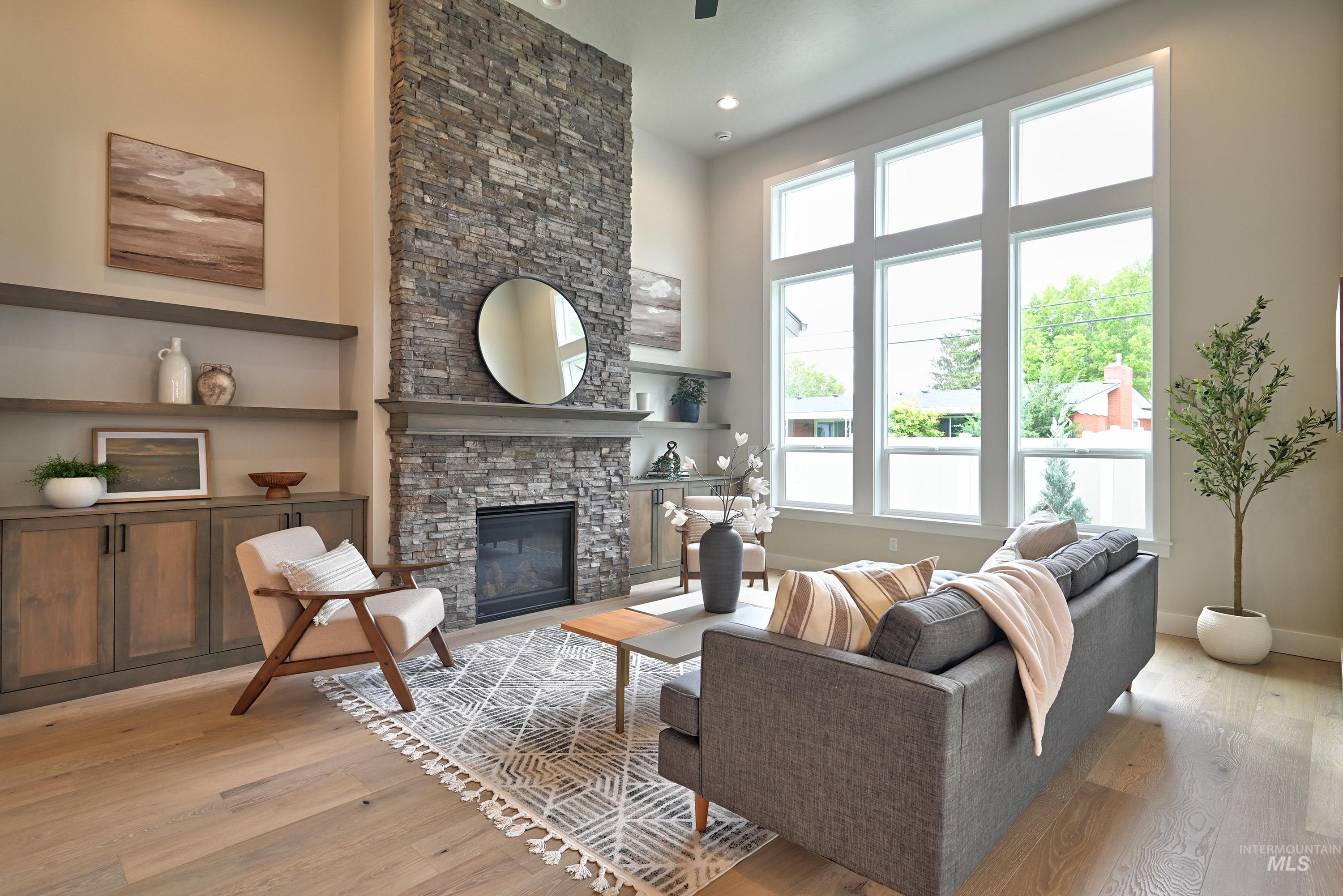 Living area with healthy amount of natural light, light wood-style flooring, a fireplace, a high ceiling, and recessed lighting