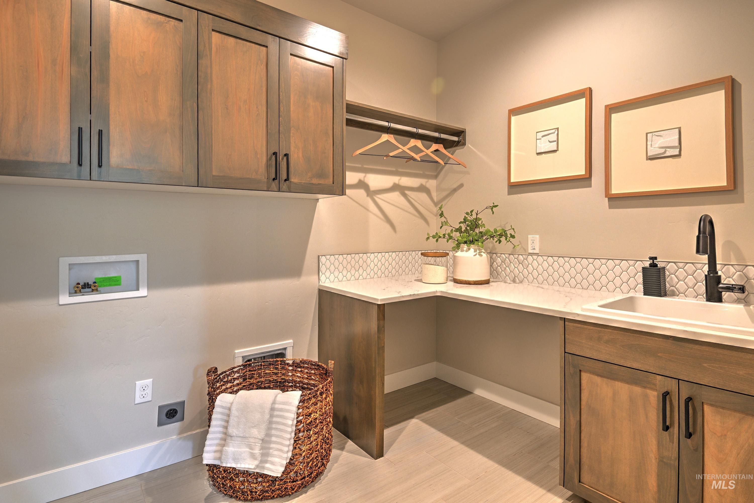 Laundry area with hookup for an electric dryer, cabinet space, hookup for a washing machine, and light wood finished floors