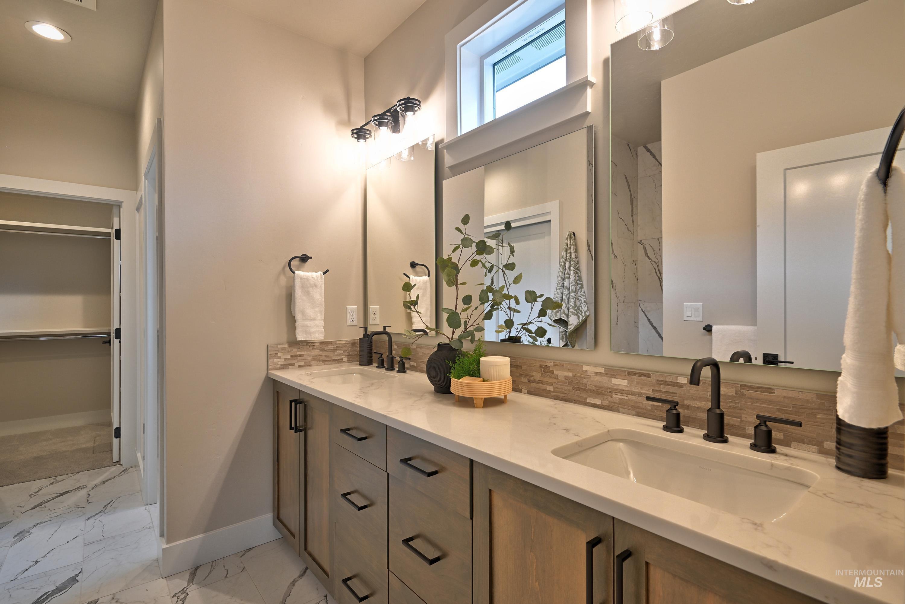 Full bathroom with marble look tile flooring, decorative backsplash, double vanity, a walk in closet, and recessed lighting