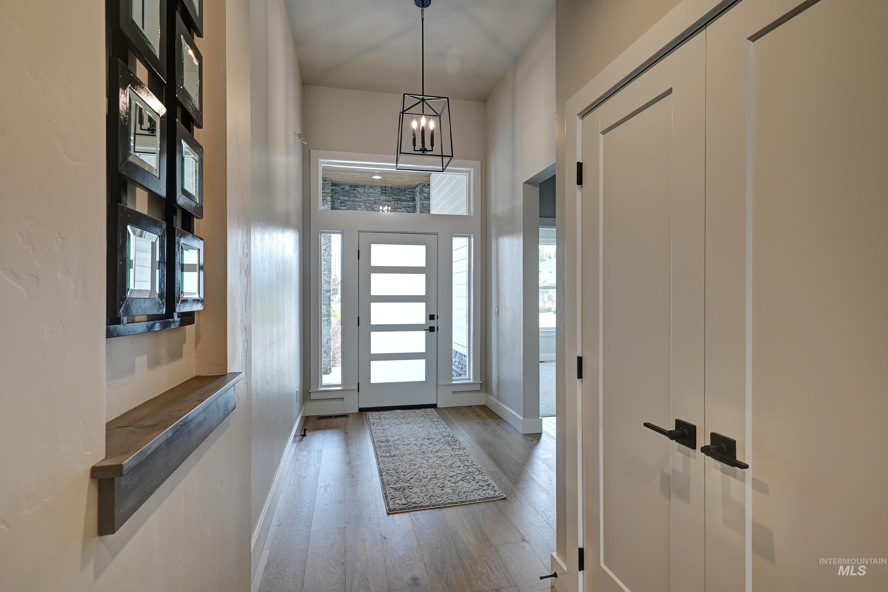 Foyer with wood finished floors, plenty of natural light, and a chandelier