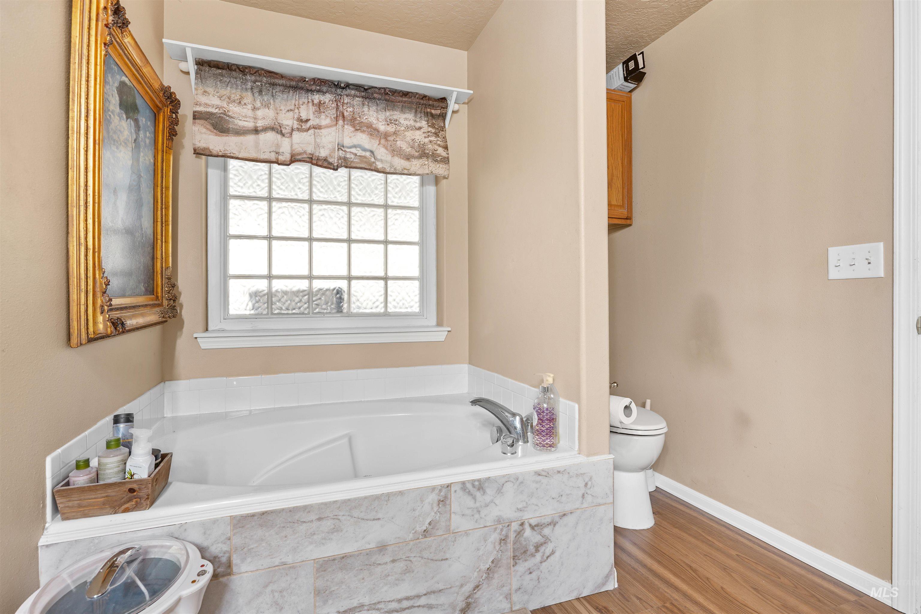 Full bath featuring a bath, wood finished floors, and a textured ceiling