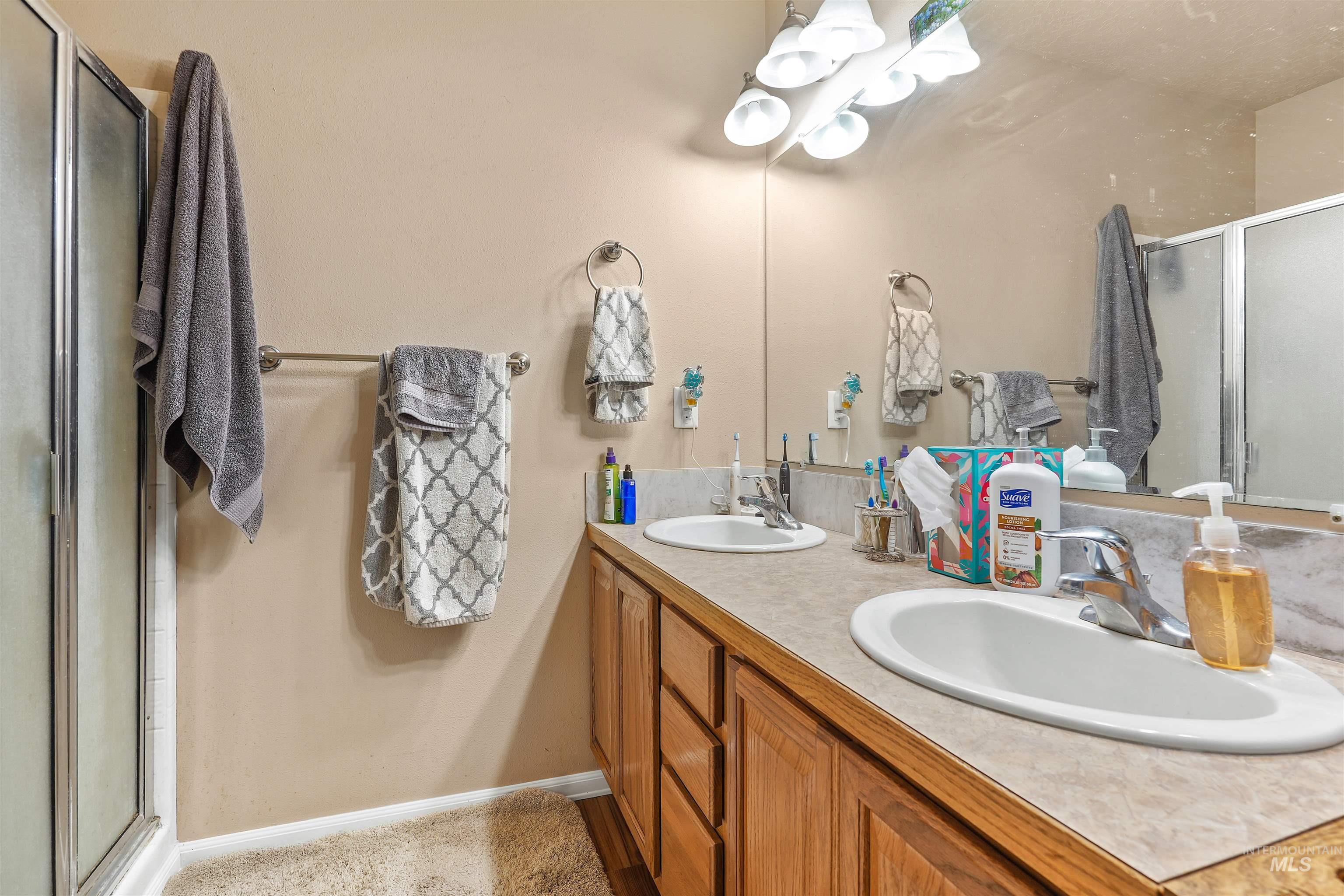 Full bathroom featuring a stall shower and double vanity
