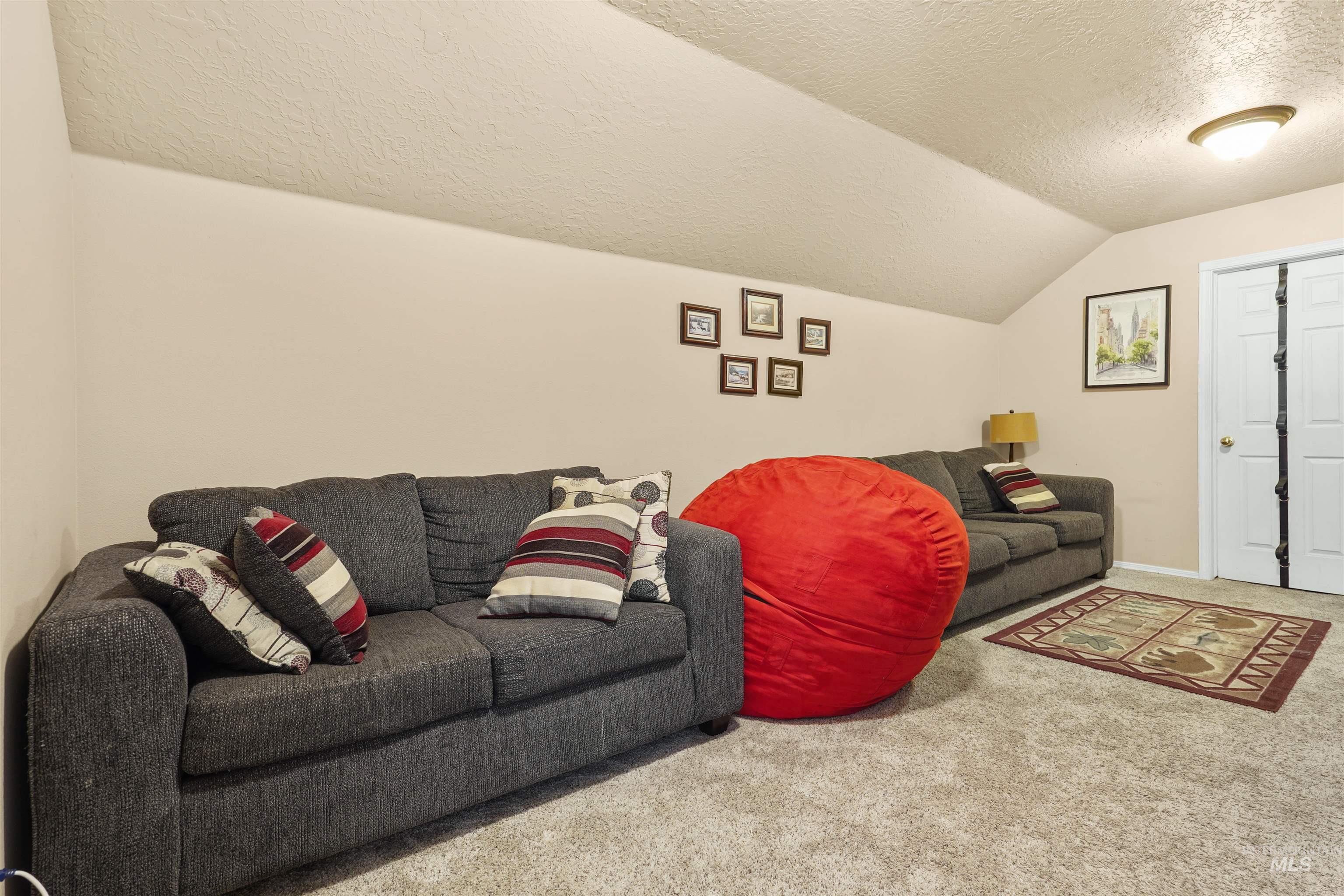 Living room with a textured ceiling, carpet, and vaulted ceiling