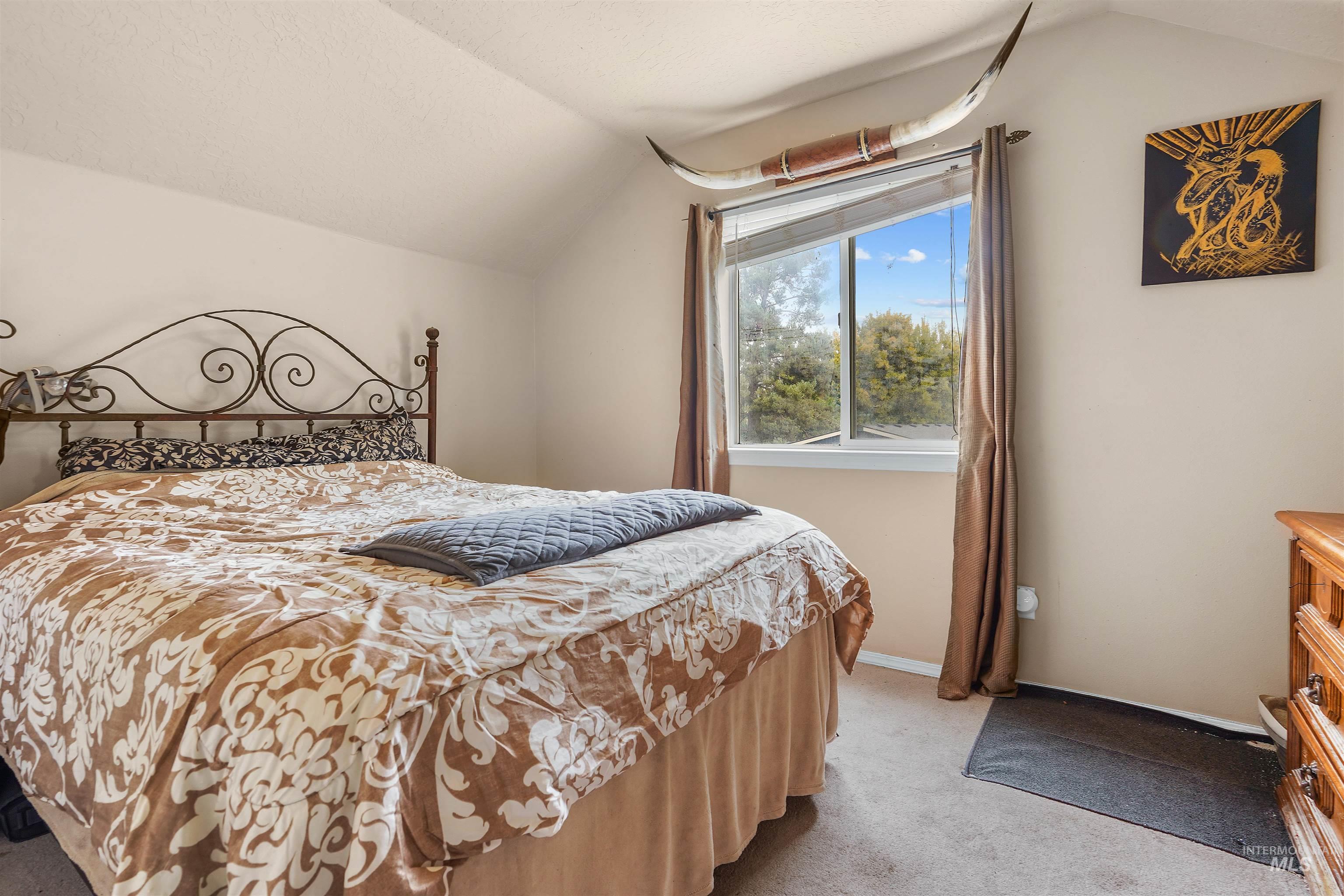 Bedroom with lofted ceiling and light colored carpet