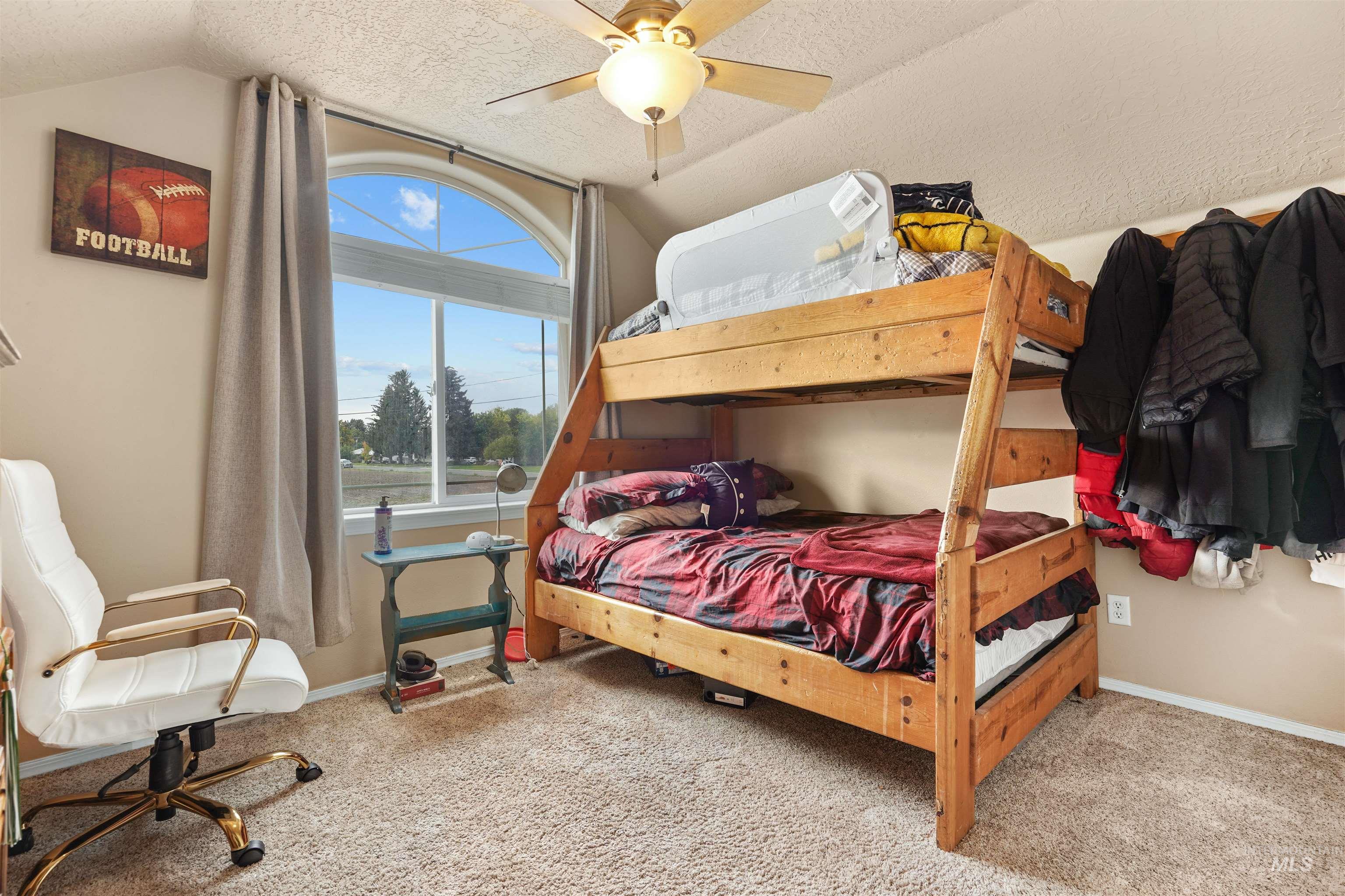 Bedroom featuring vaulted ceiling, light carpet, a textured ceiling, and ceiling fan