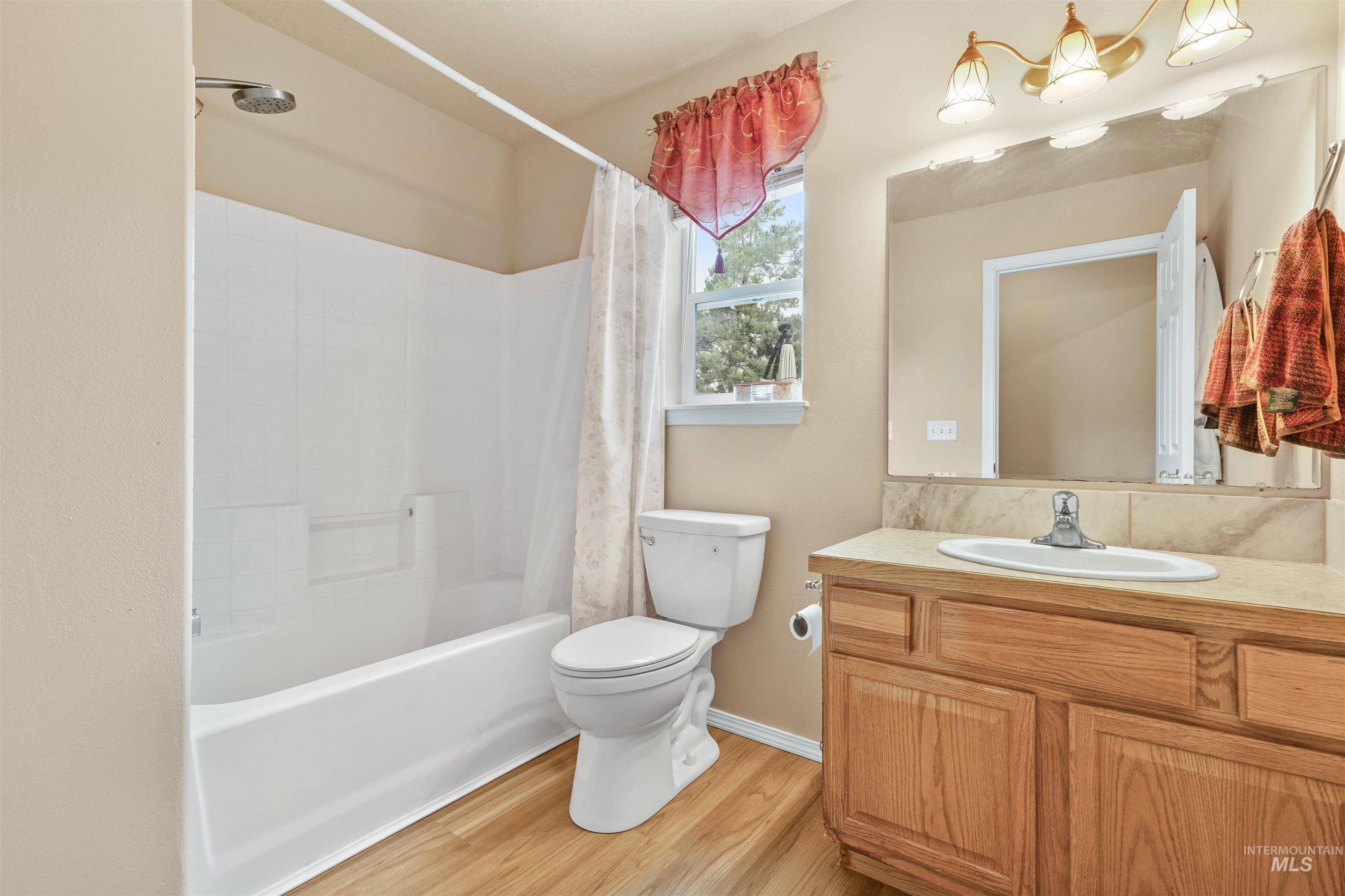 Full bathroom with shower / bath combo, light wood-style flooring, and vanity
