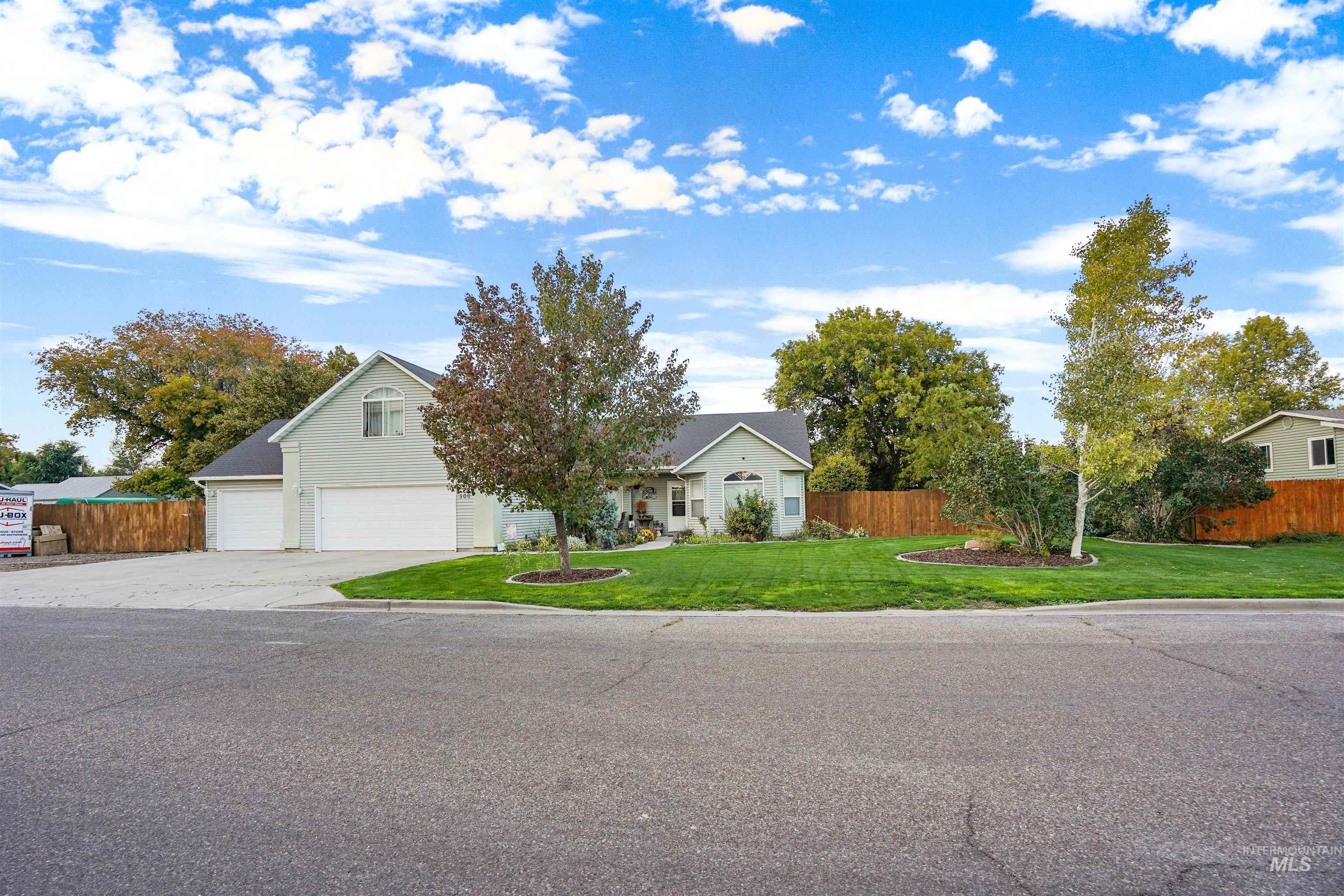 View of property hidden behind natural elements featuring concrete driveway