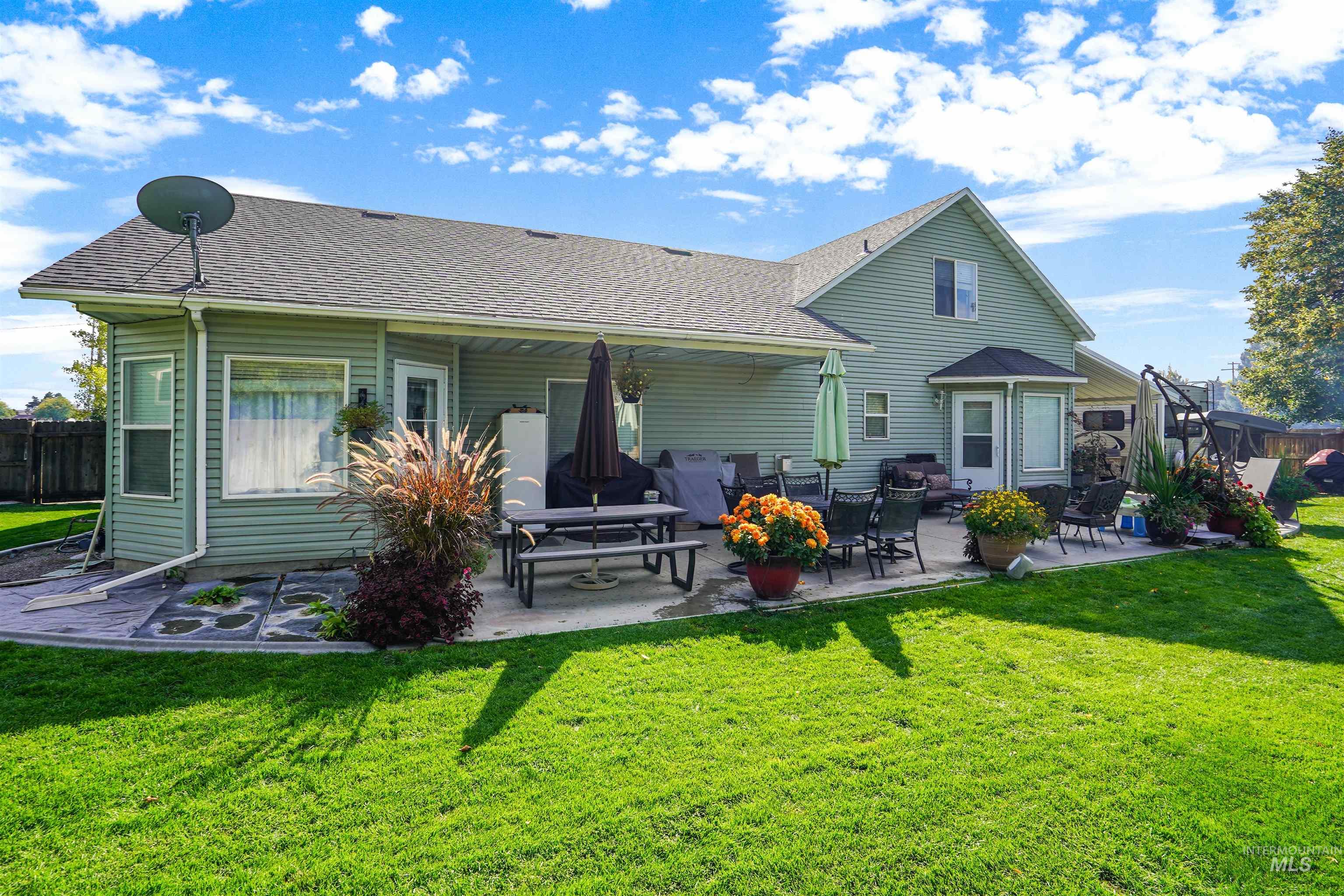 Rear view of house featuring a patio and a shingled roof
