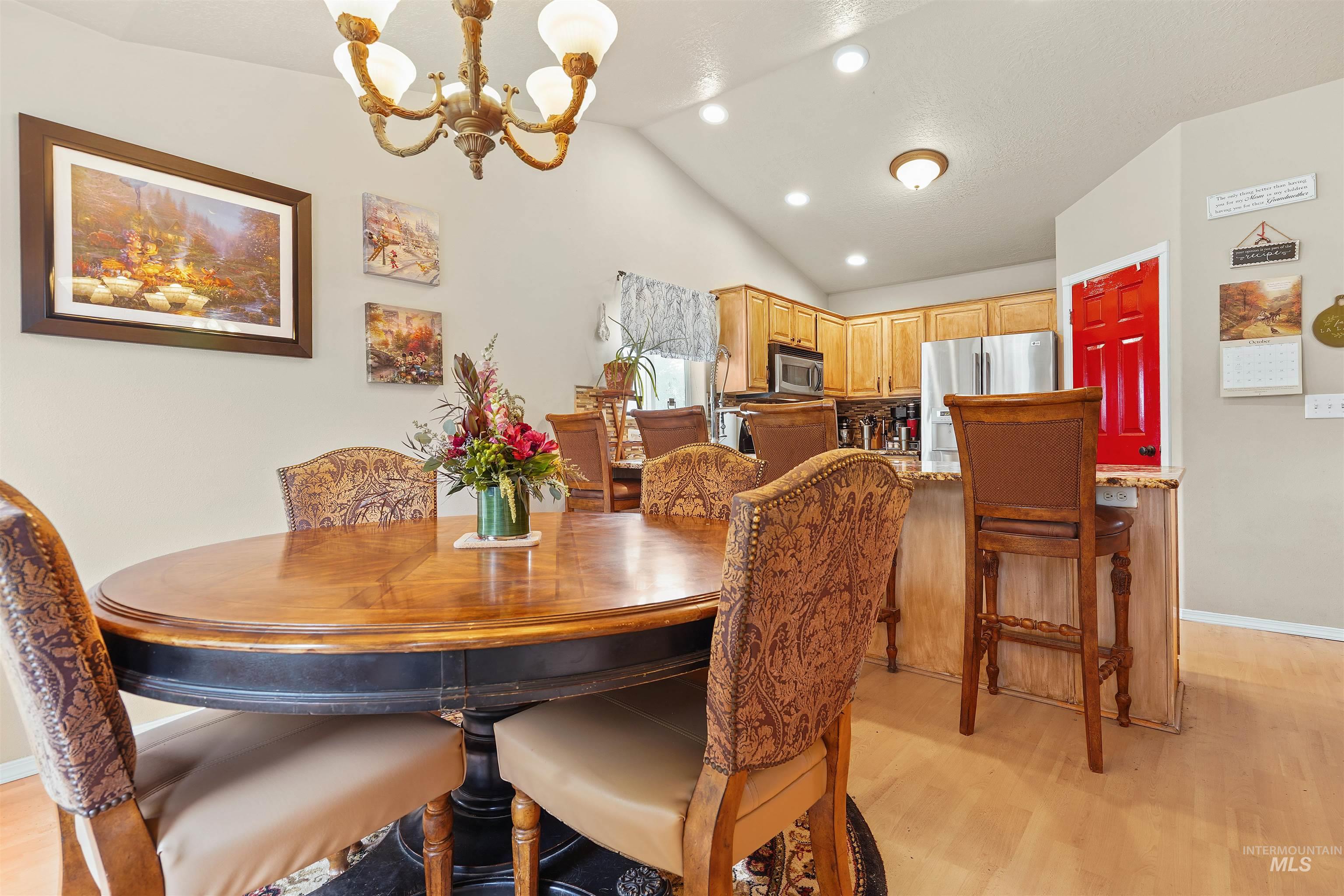 Dining room featuring light wood finished floors, recessed lighting, a chandelier, and vaulted ceiling