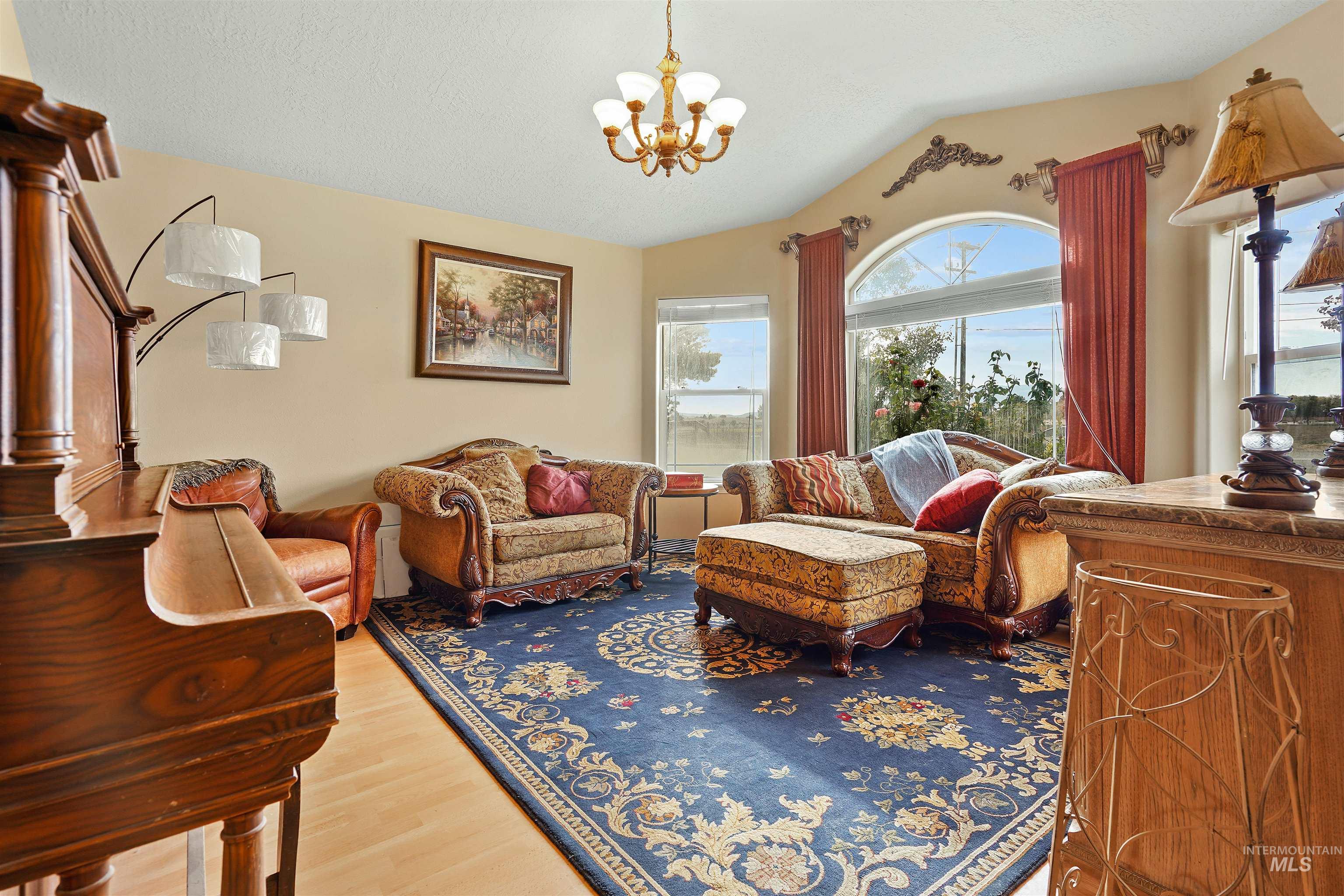 Sitting room with vaulted ceiling, a chandelier, and light wood-style floors