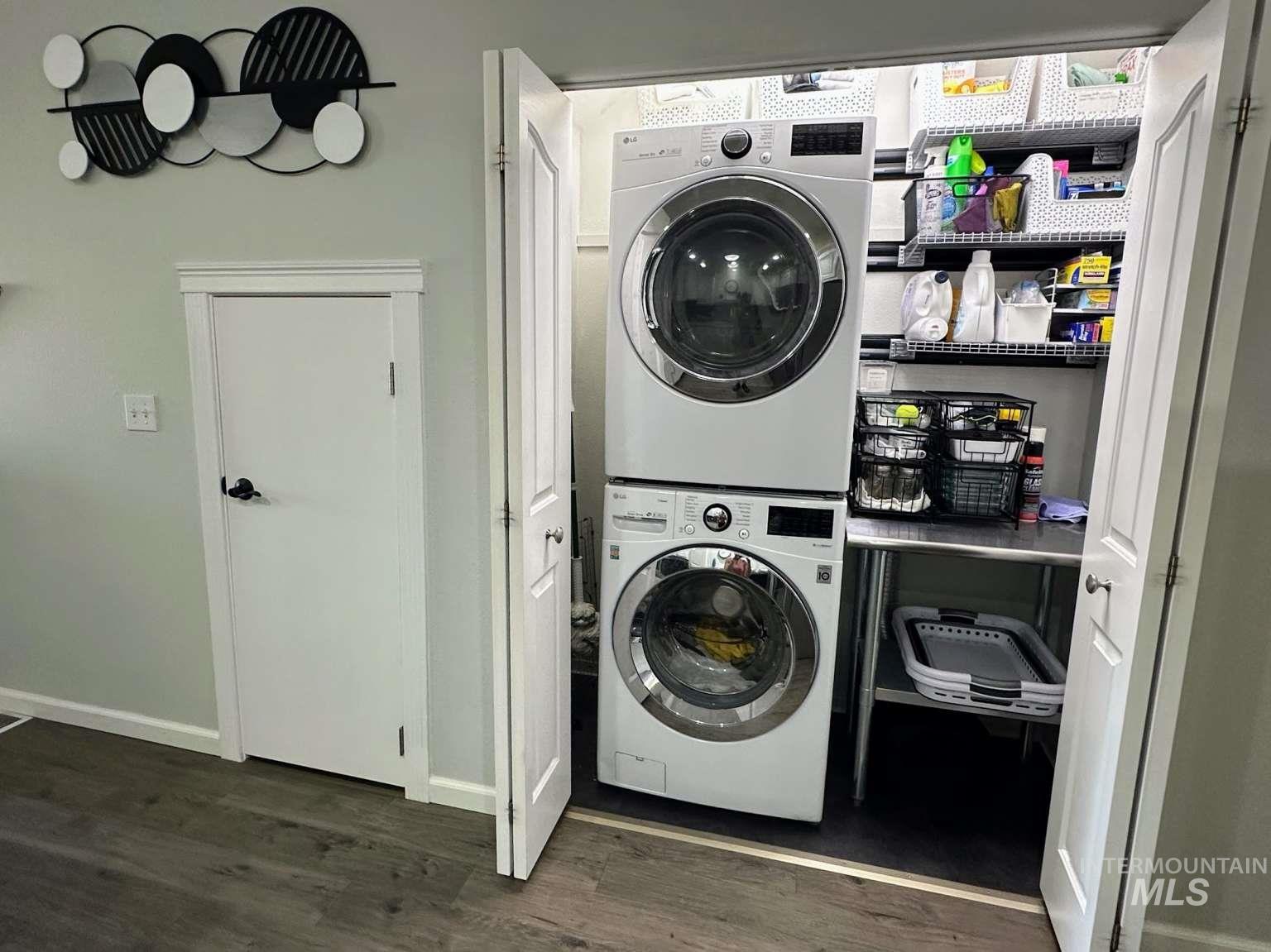 Laundry area with stacked washer / dryer and dark wood-style floors