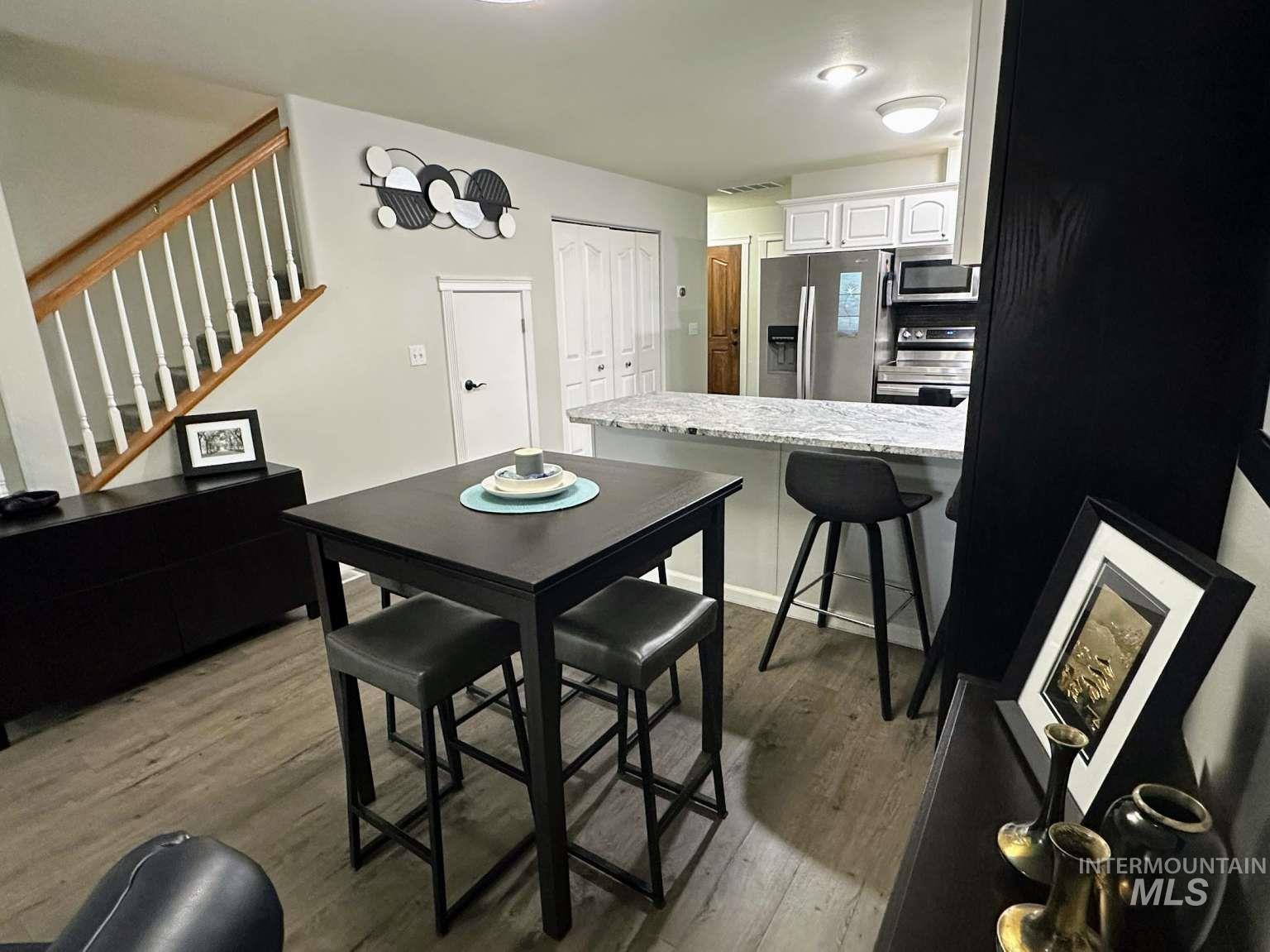 Dining room with dark wood-style floors and stairway