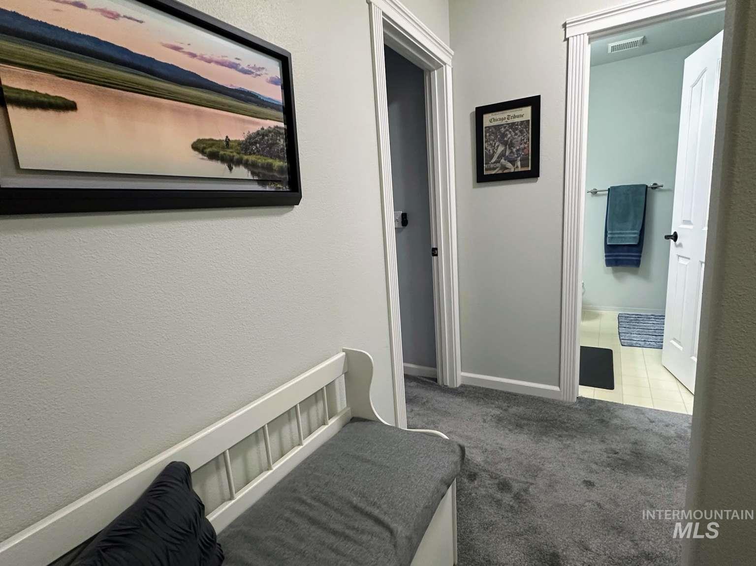 Corridor with light carpet, a textured wall, and light tile patterned floors