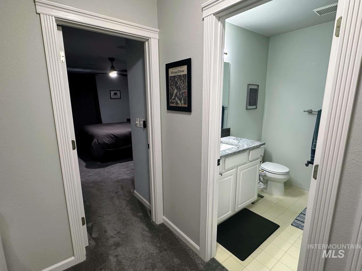 Bathroom featuring vanity, light tile patterned floors, light colored carpet, and ceiling fan