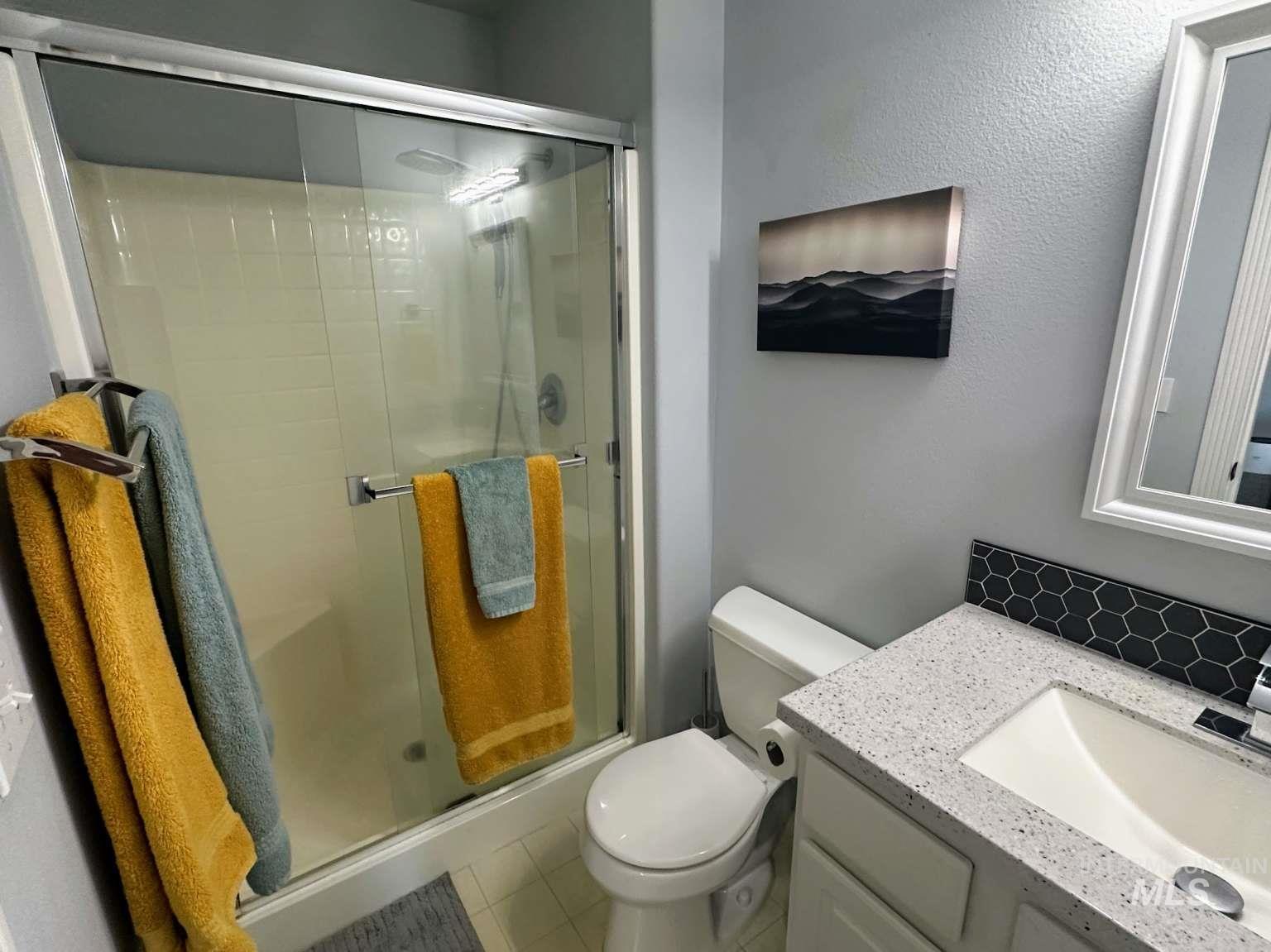 Full bath with vanity, a shower stall, and light tile patterned floors