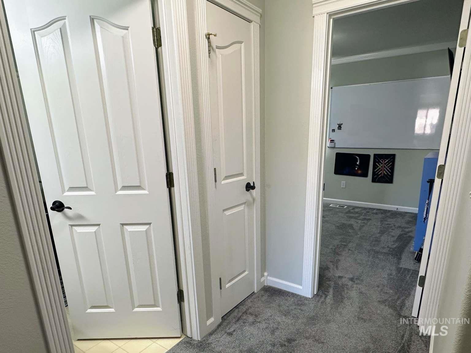 Corridor featuring dark carpet and baseboards