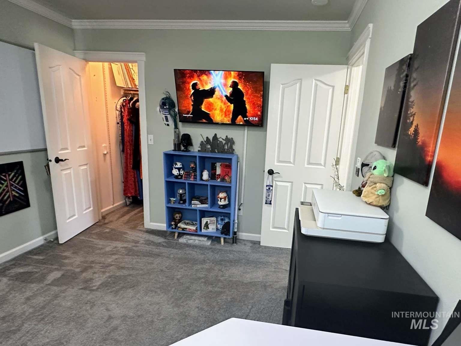 Bedroom featuring dark colored carpet, a spacious closet, and crown molding
