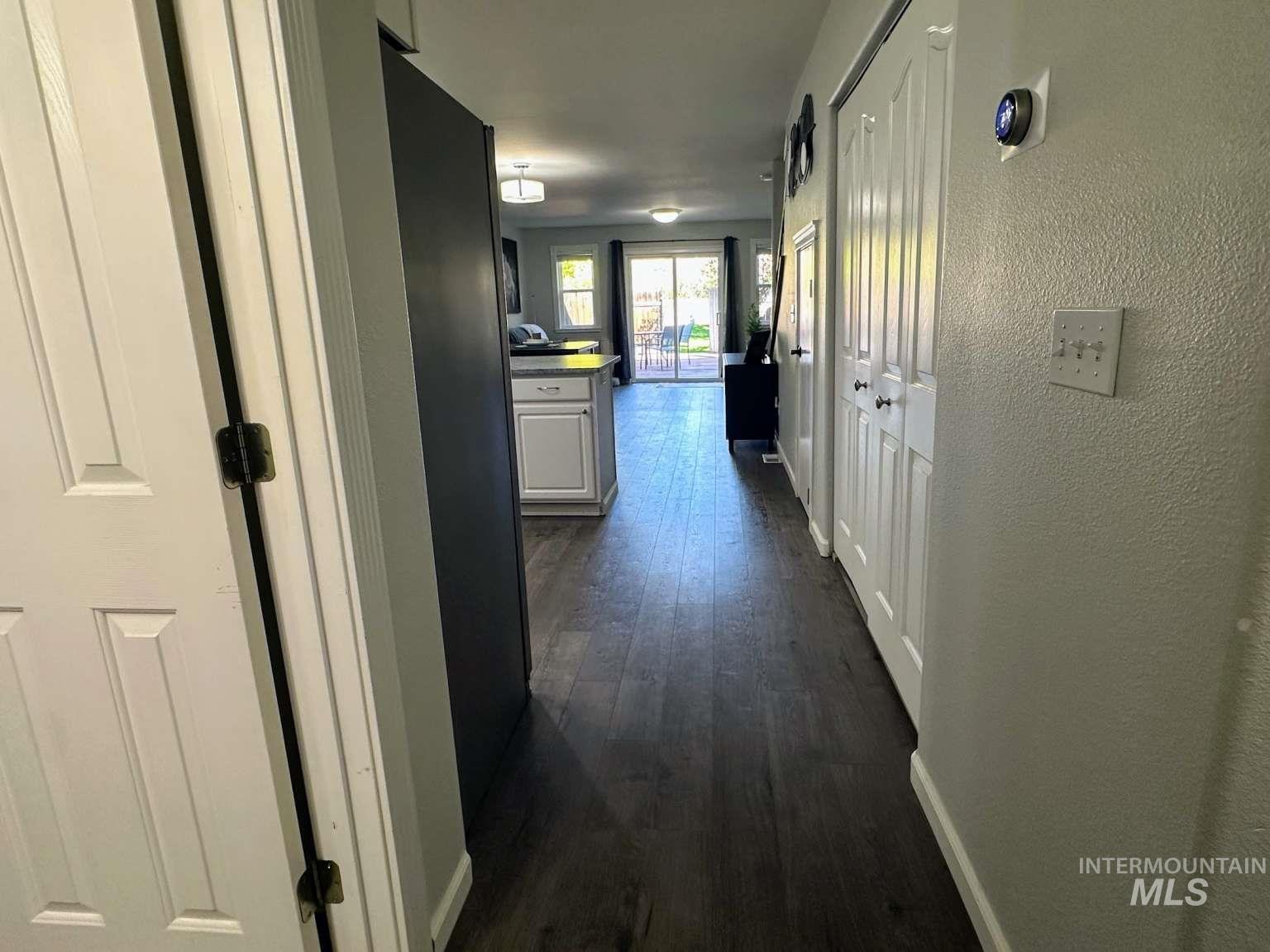 Hallway with a textured wall and dark wood finished floors
