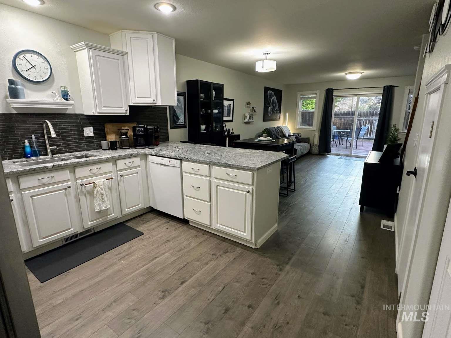 Kitchen featuring a peninsula, decorative backsplash, open floor plan, and light wood finished floors