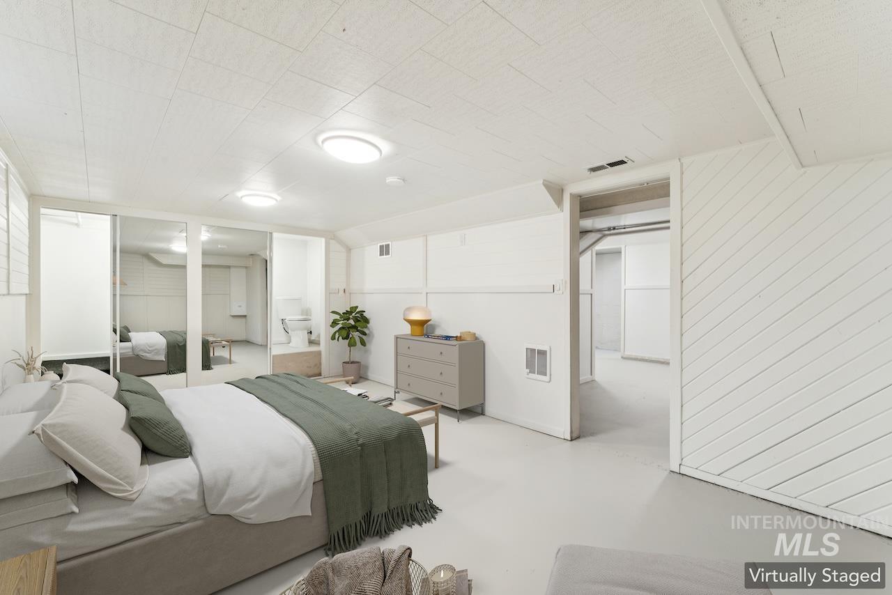 Bedroom with concrete floors, a closet, and wooden walls