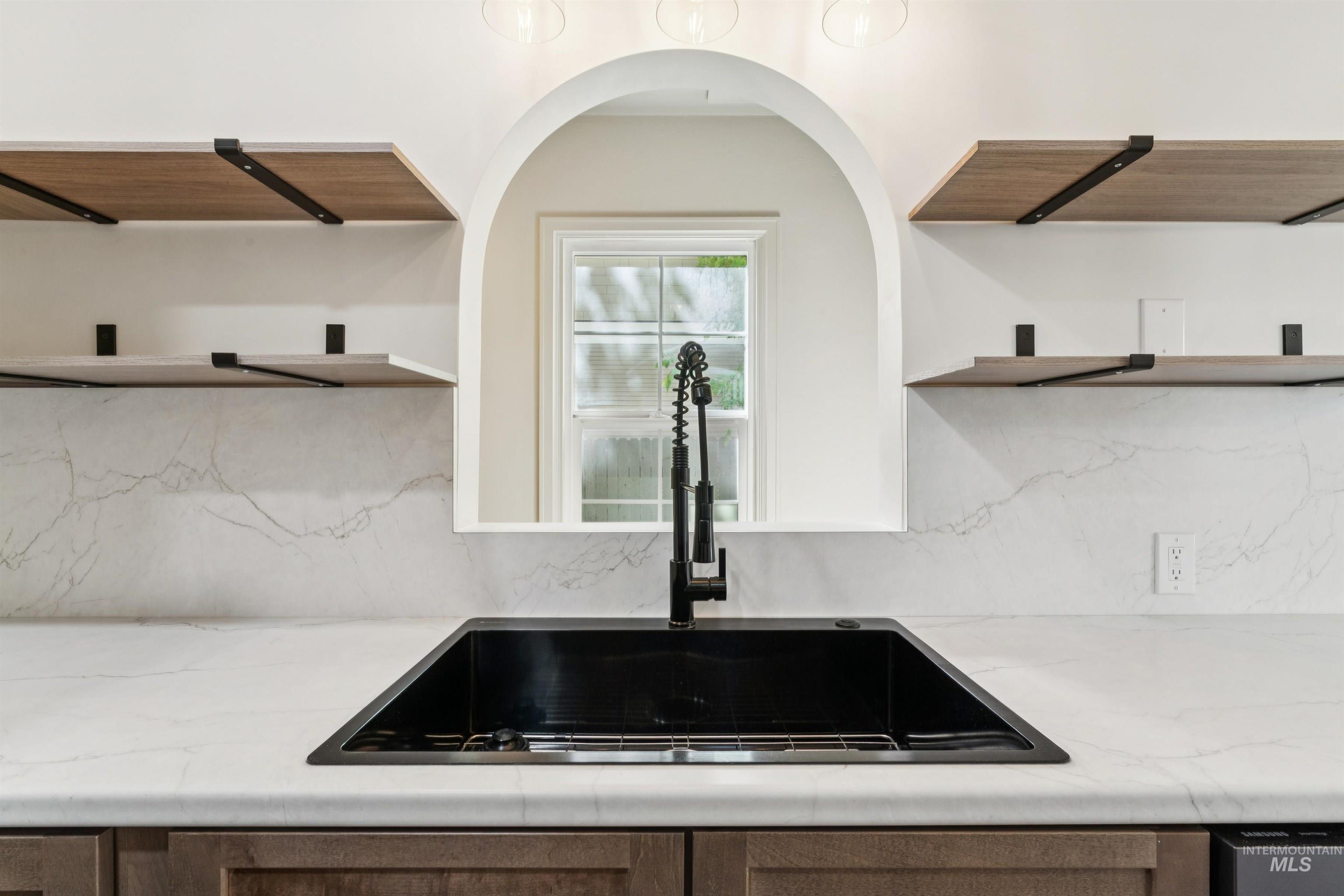 Kitchen with open shelves, backsplash, and light stone countertops