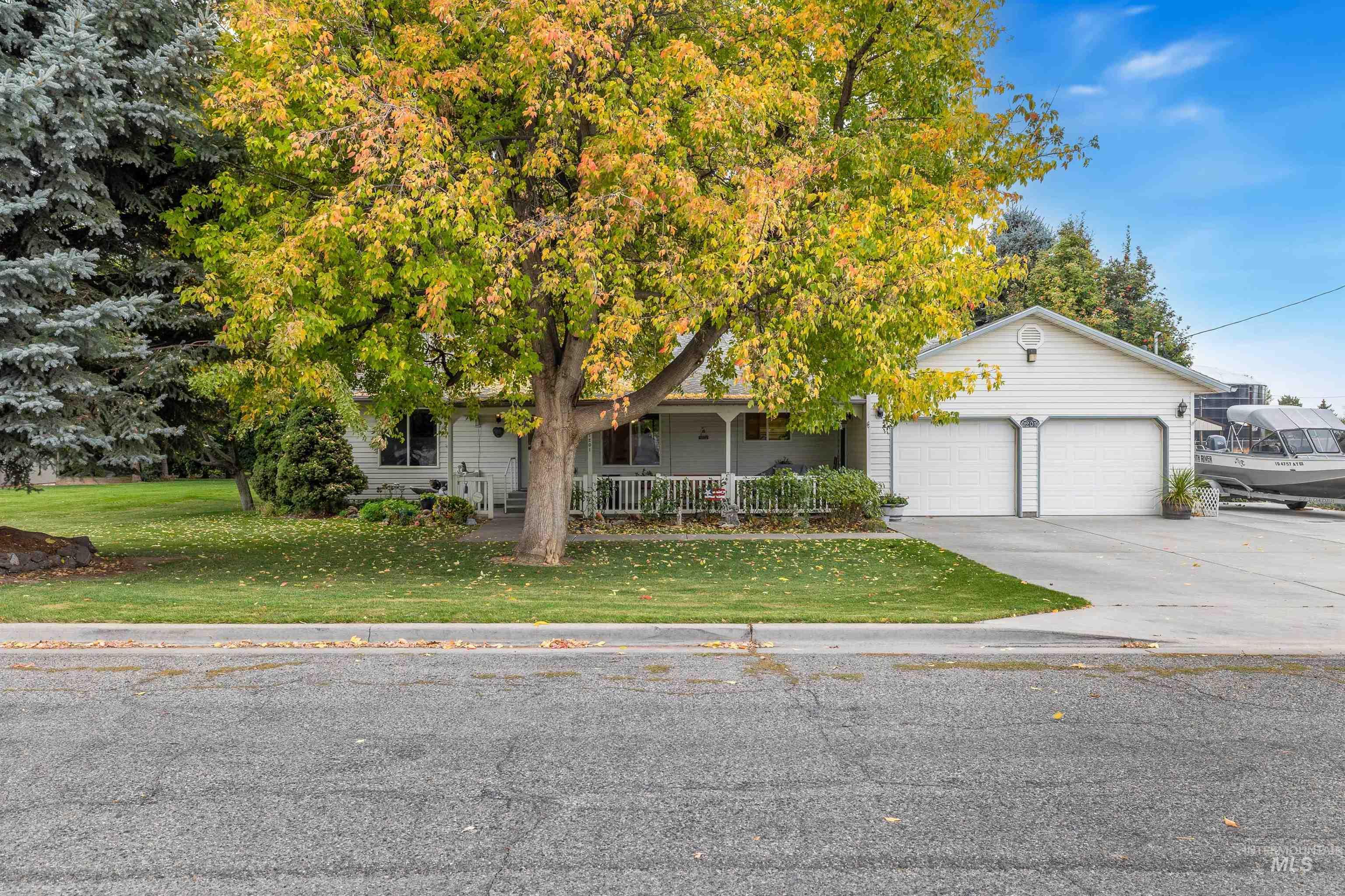 Obstructed view of property with covered porch, concrete driveway, a front yard, and a garage