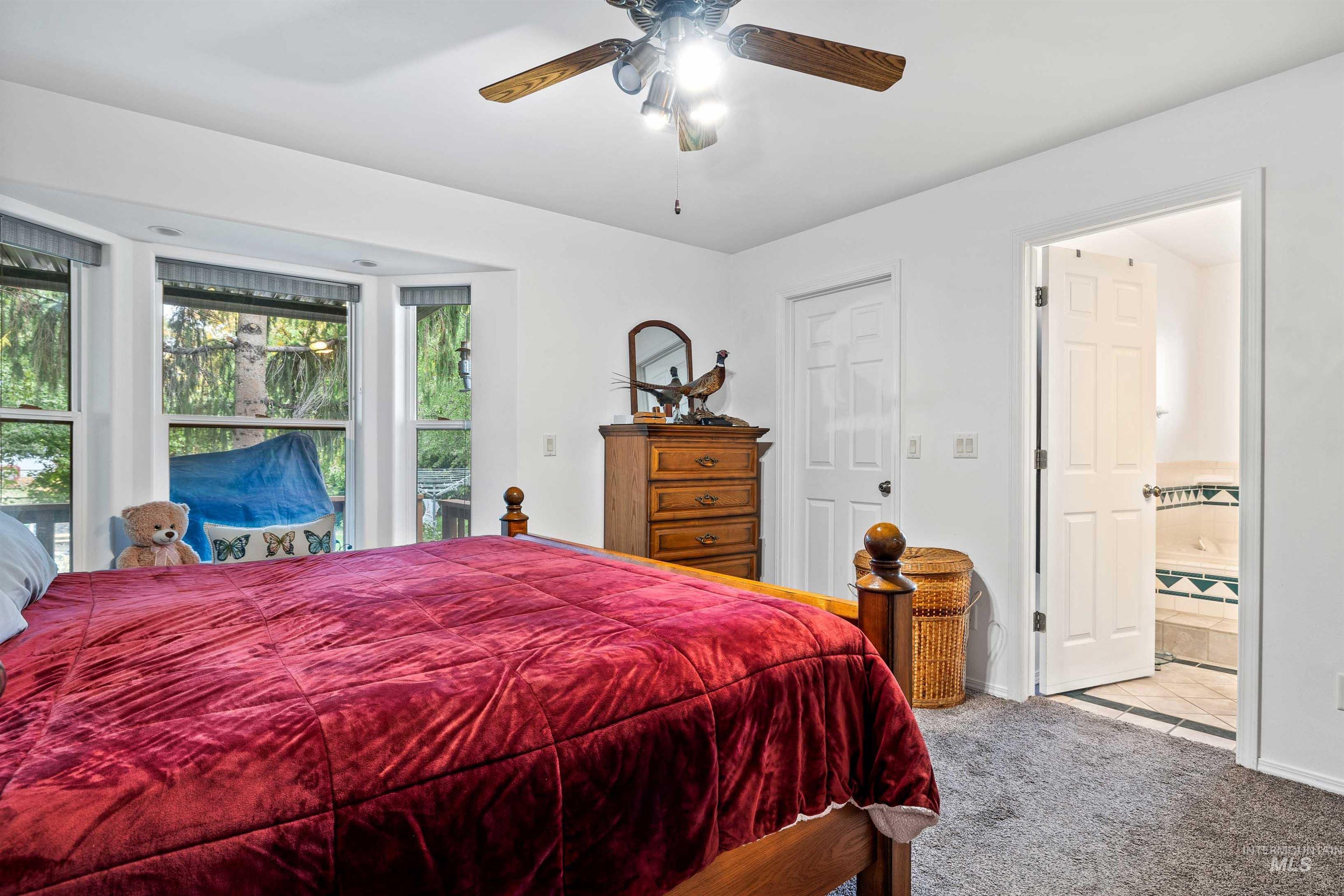 Carpeted bedroom with ceiling fan, connected bathroom, and tile patterned flooring
