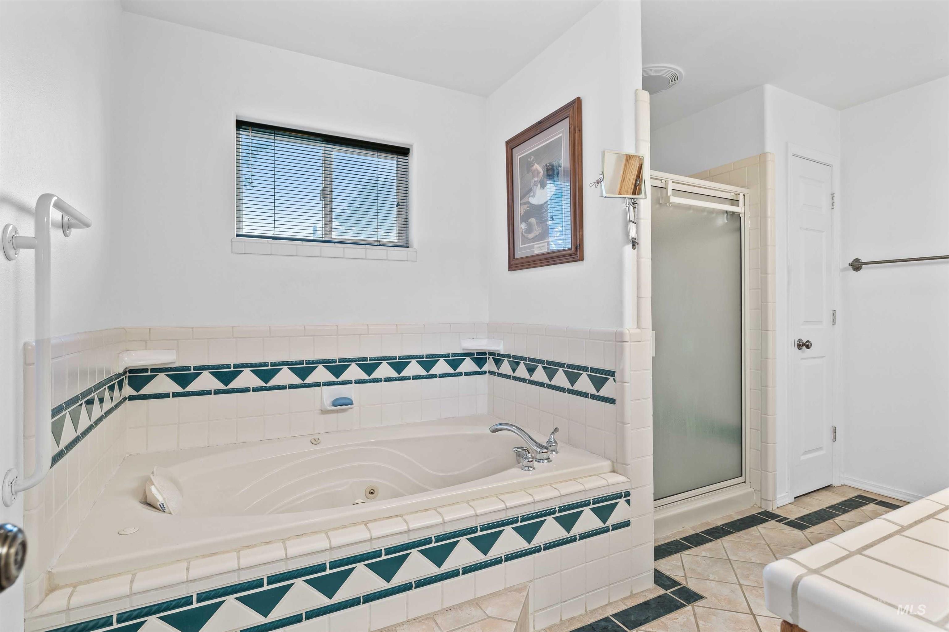 Full bath with a shower stall, light tile patterned floors, and a jetted tub