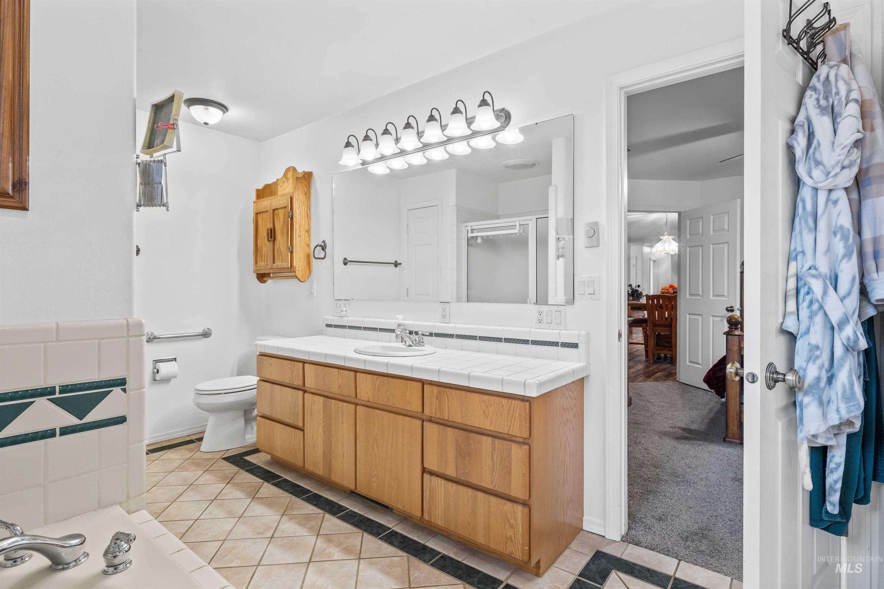 Full bath with light tile patterned floors, vanity, a stall shower, light carpet, and a bath
