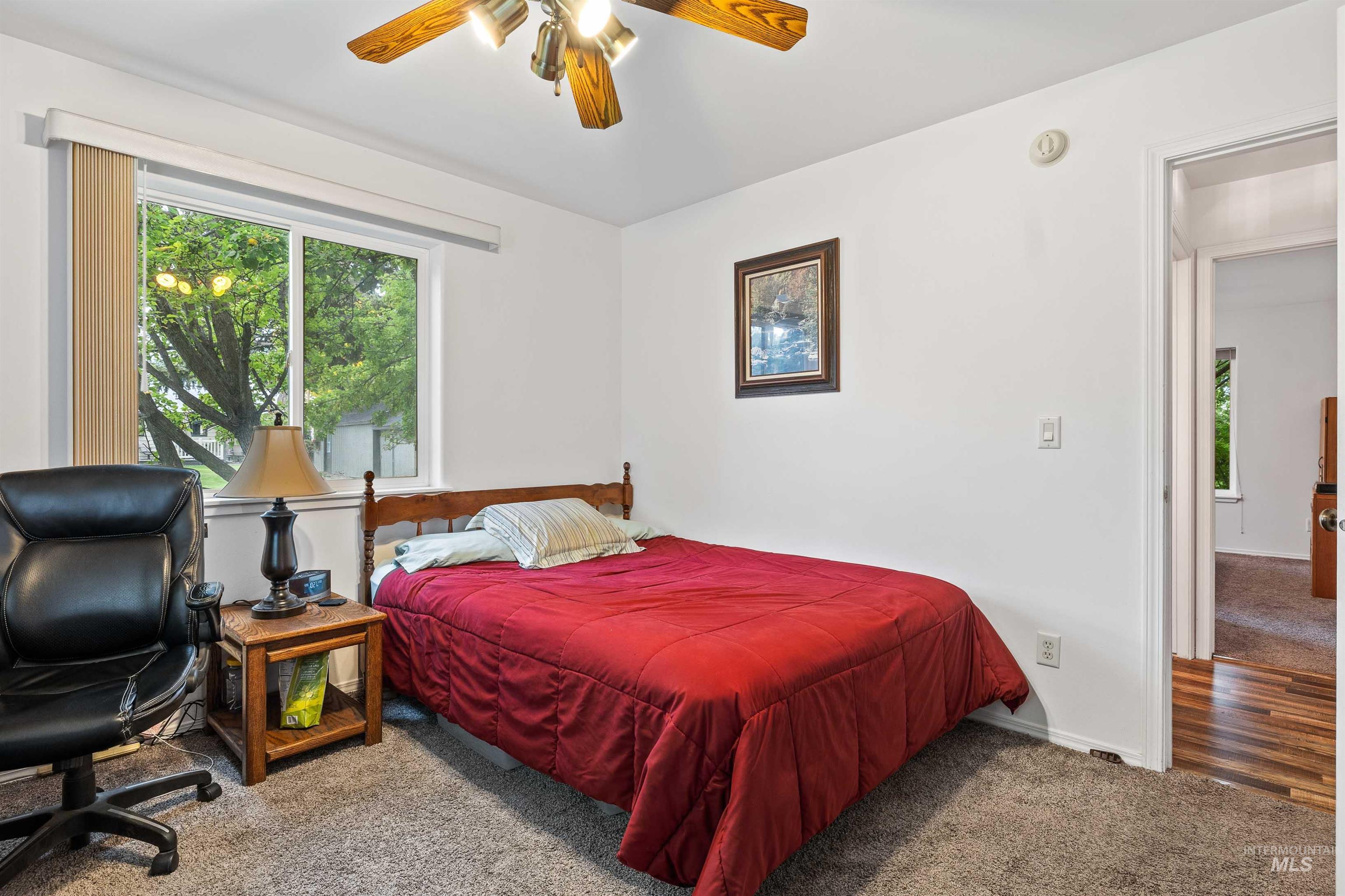 Bedroom with carpet flooring, multiple windows, and ceiling fan