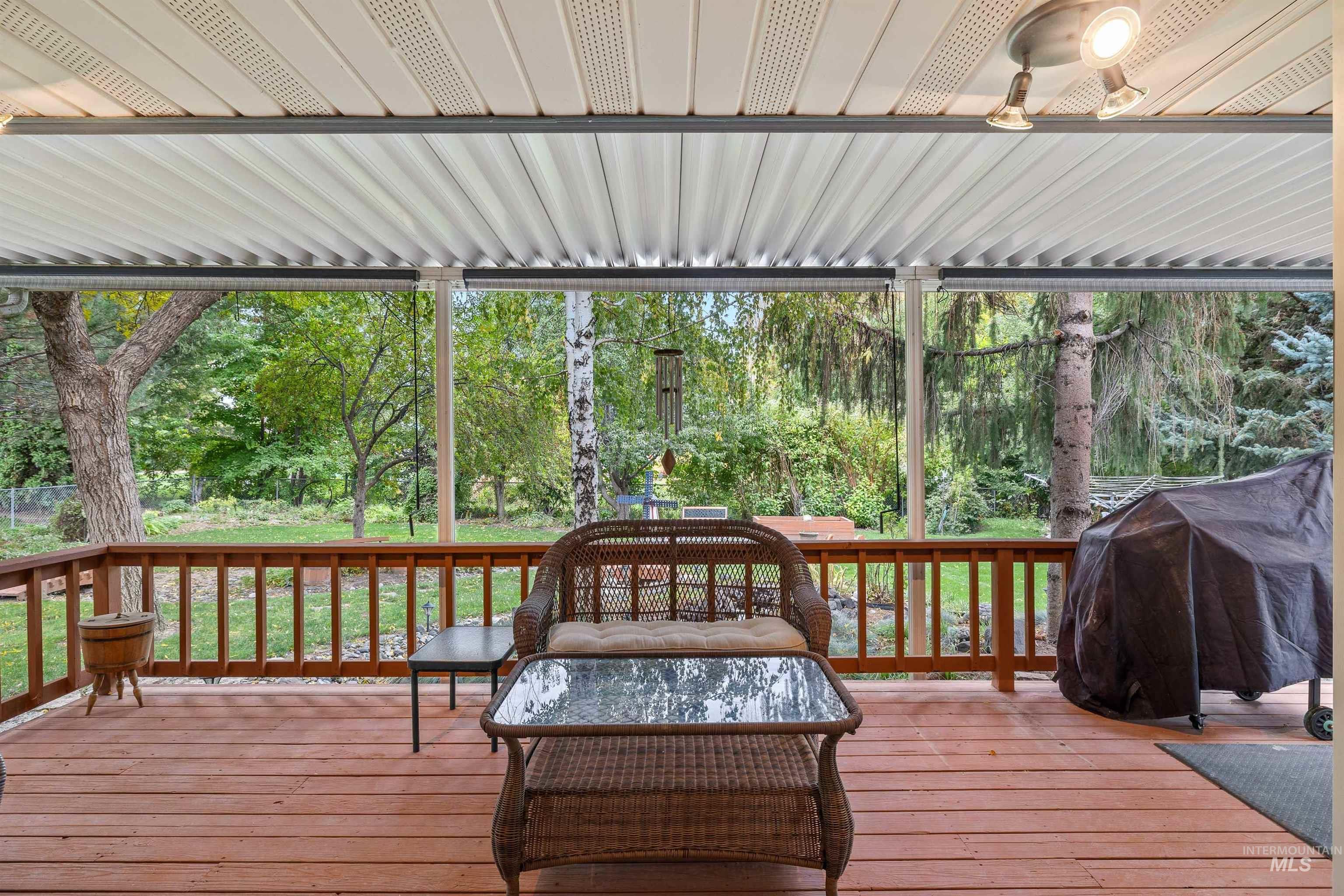 Wooden terrace featuring view of wooded area, grilling area, and a yard