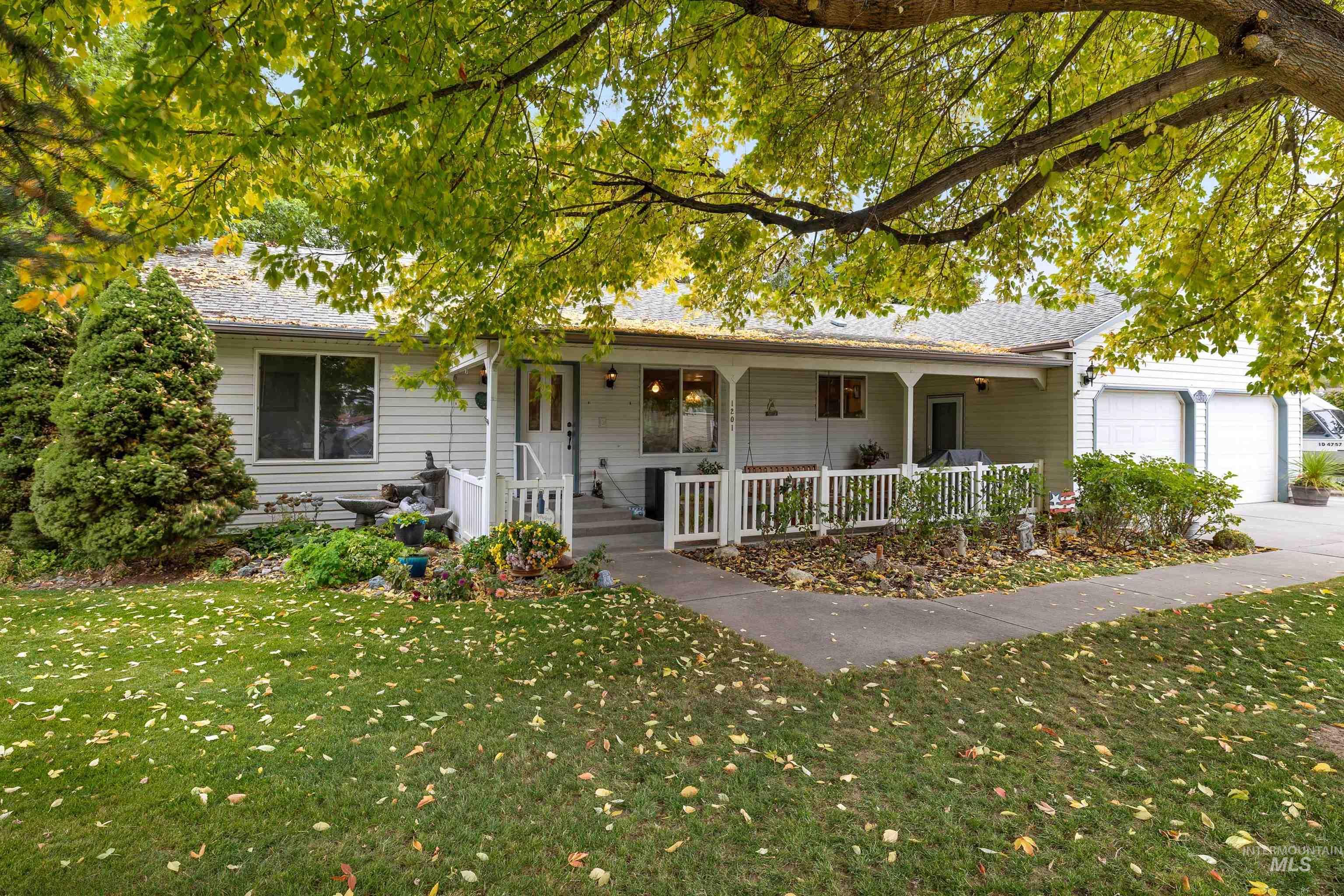 Ranch-style home with covered porch, a front yard, and an attached garage