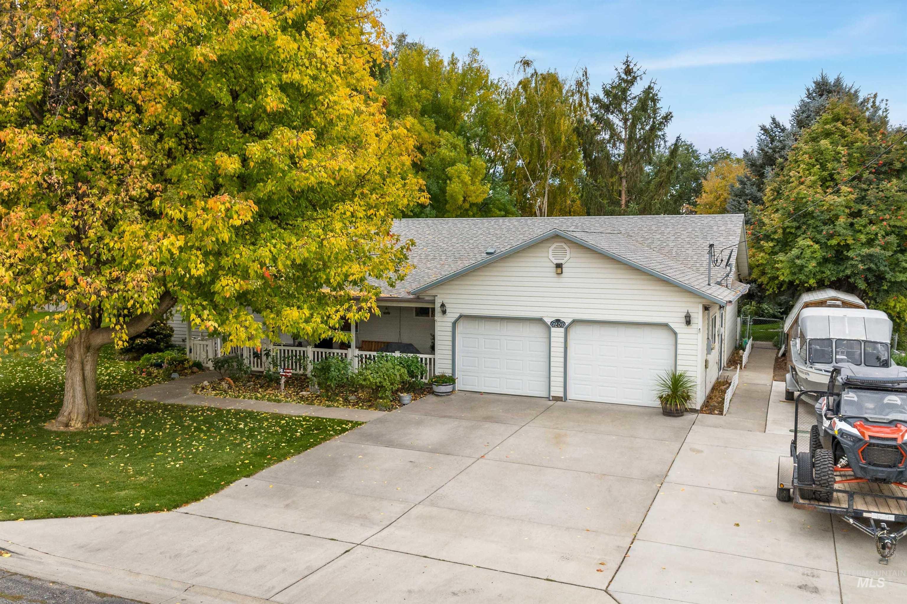 View of front of property featuring concrete driveway, roof with shingles, an attached garage, and a front yard